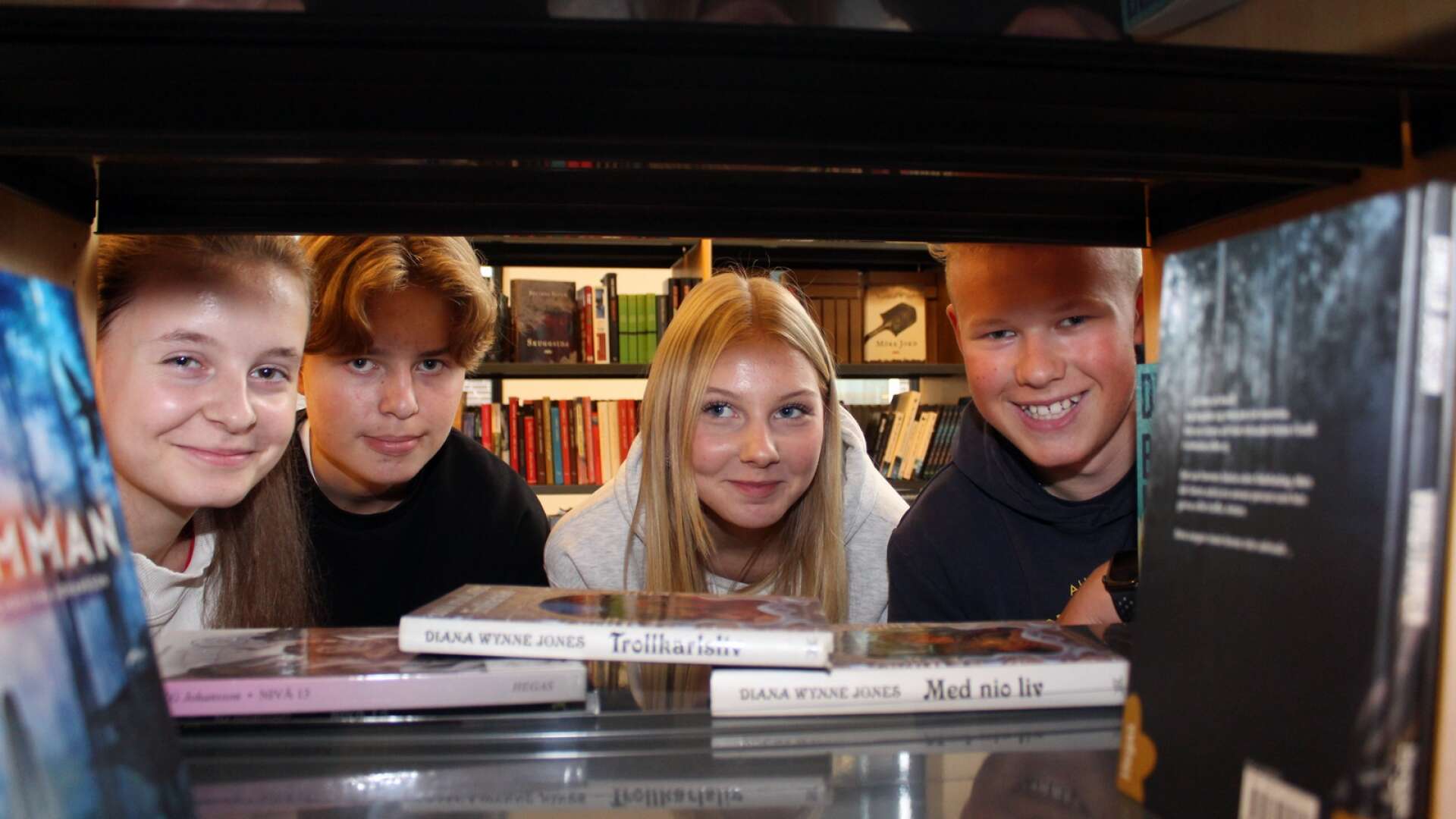 Maja Samueljord, Melvin Weghammar, Lova Bäckman Dahlström och Gustav Skålén i elevrådet på Tegnérskolan tittar fram i en bokhylla på skolans nyinvigda bibliotek. 