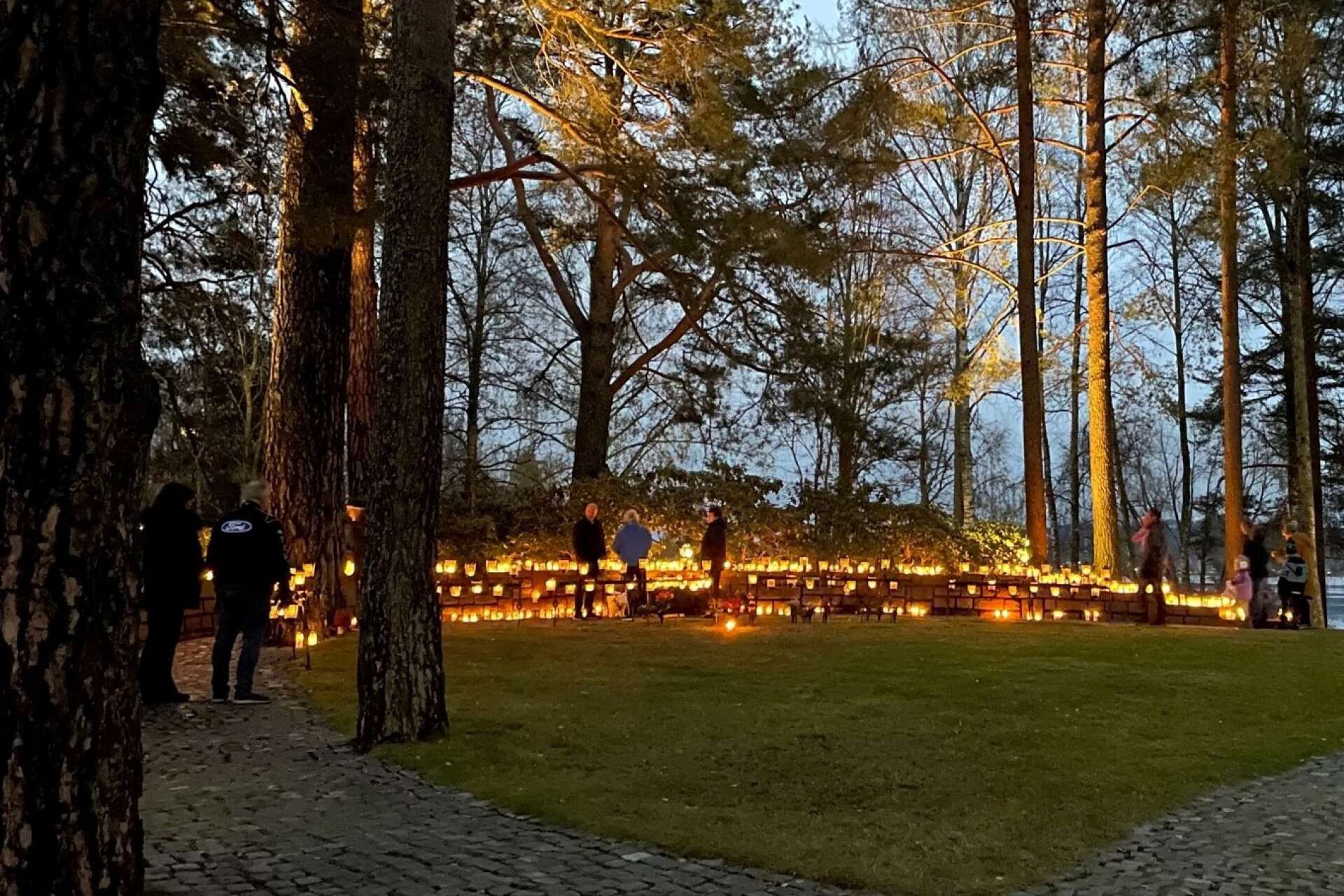 Minneslunden på kyrkogården i Arvika lördag kväll. Stenmuren var täckt av ljus som brann i mörkret. 