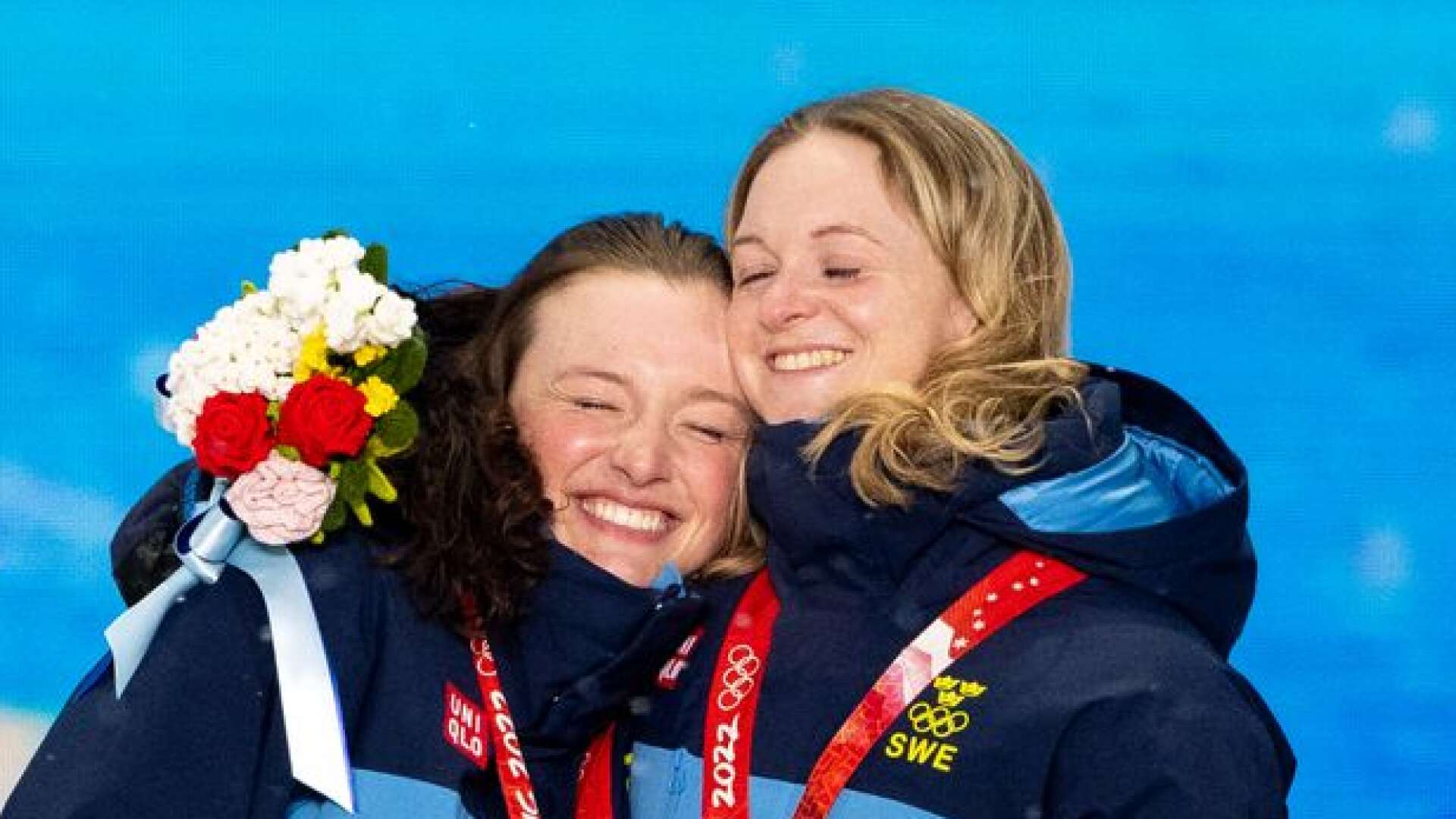 Värmländskorna Linn Persson och Mona Brorsson kramar om varandra på prisutdelningen efter stafettguldet i Peking-OS.