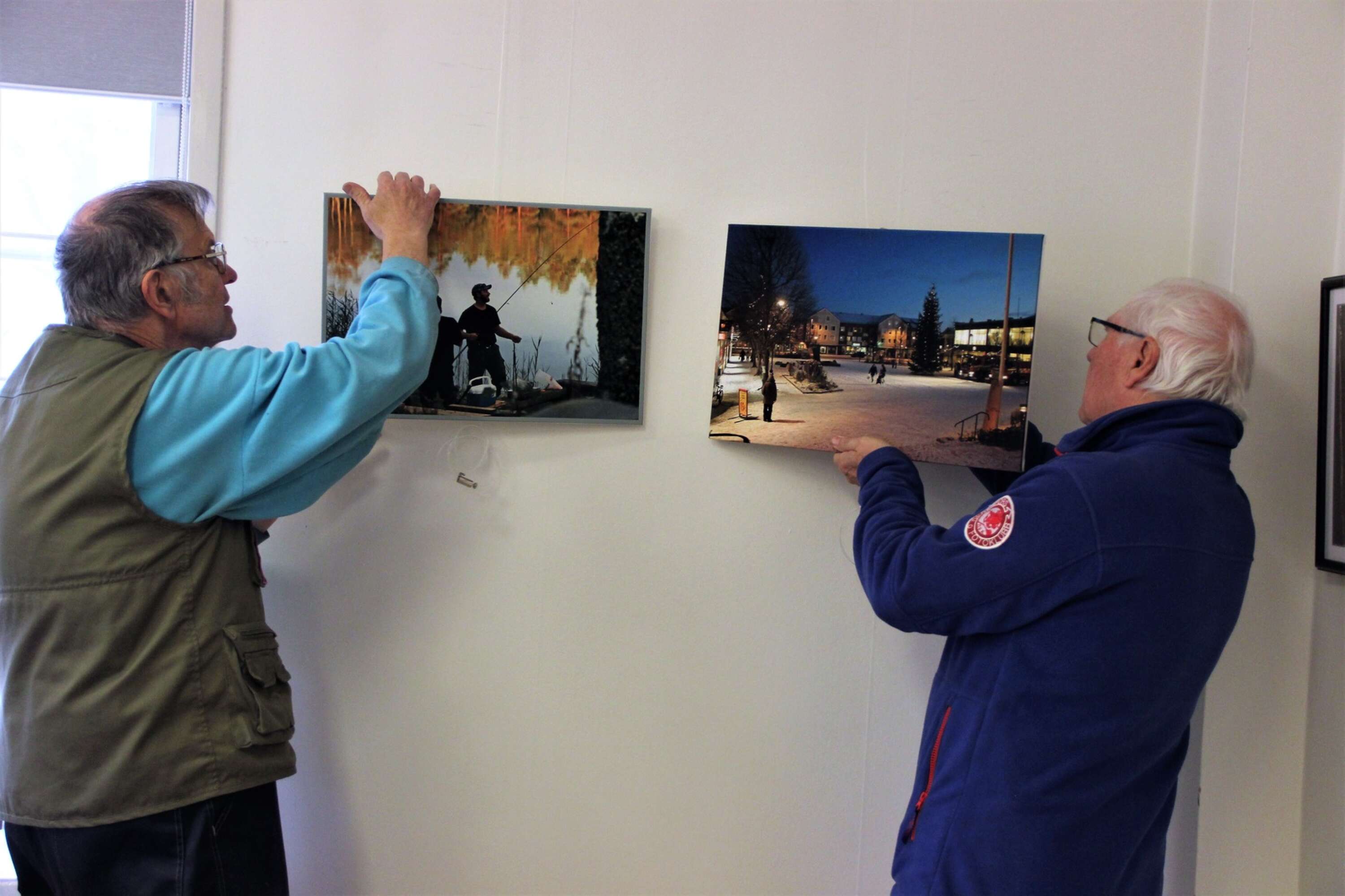 Degerfors fotoklubbs nestor Lennart Gustafson och ordförande Hans Blomqvist hänger ett par bilder av Blomqvist.