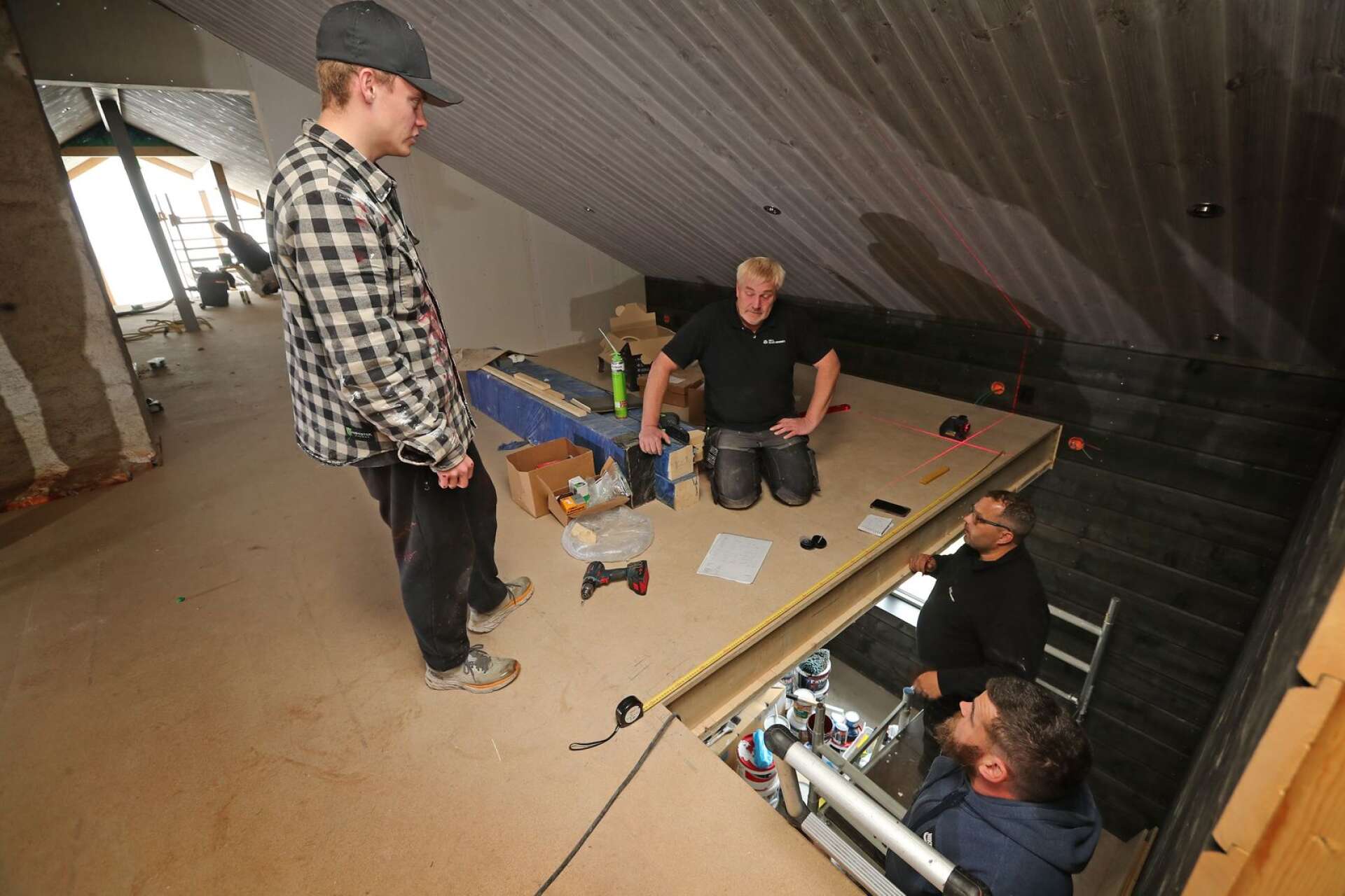 Oliver och byggföretagets ägare Ulf Nygren (närmast i trappan) gör upp planen med norrmännen som sätter upp glasväggen. De är i gemensamma spel/gästrummet.