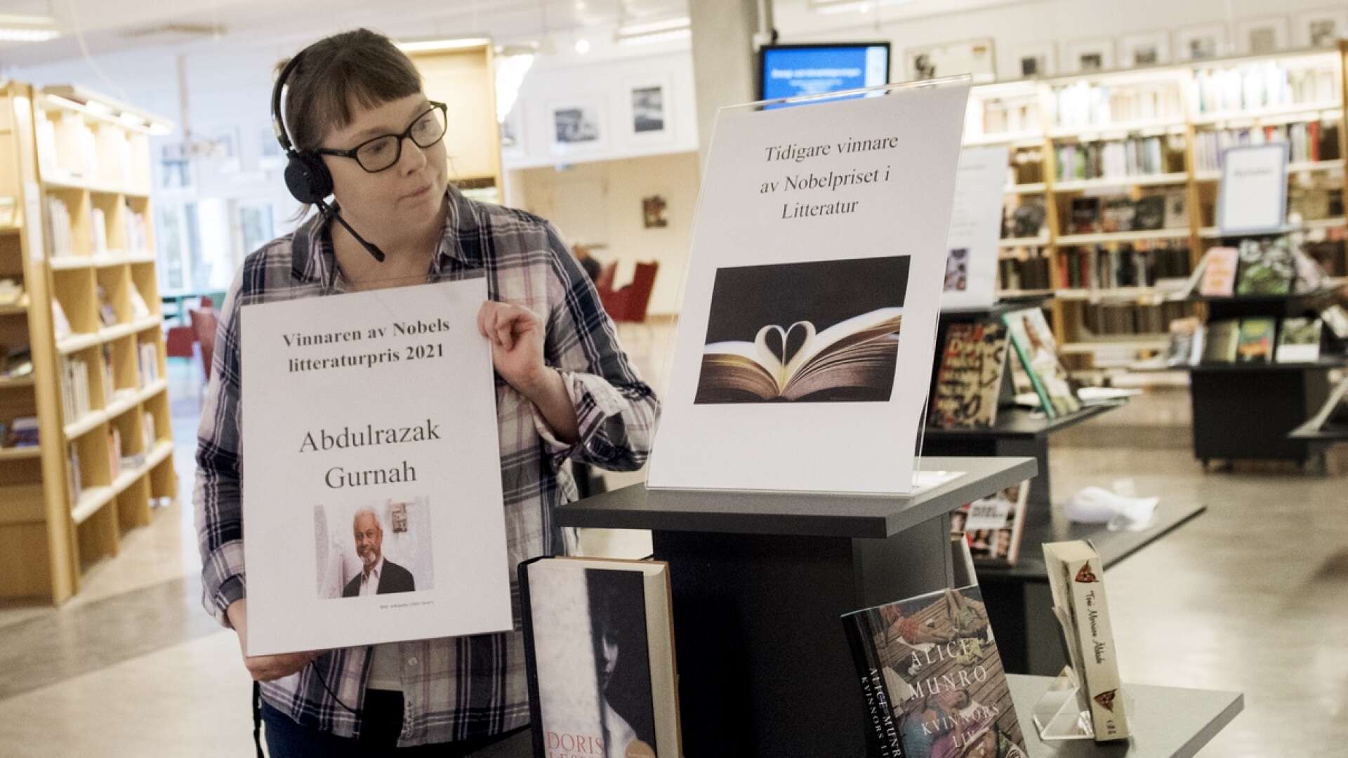 Inne i biblioteket har det placerats en pyramid med tidigare års Nobelpristagare i litteratur. Liselott Jensen placerar en skylt med 2021 års pristagare på ett bord framför.