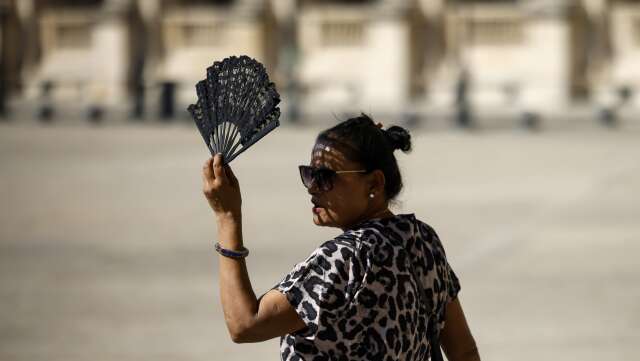 En kvinna försöker svalka sig med en solfjäder i Paris i början av september i år. Arkivbild.