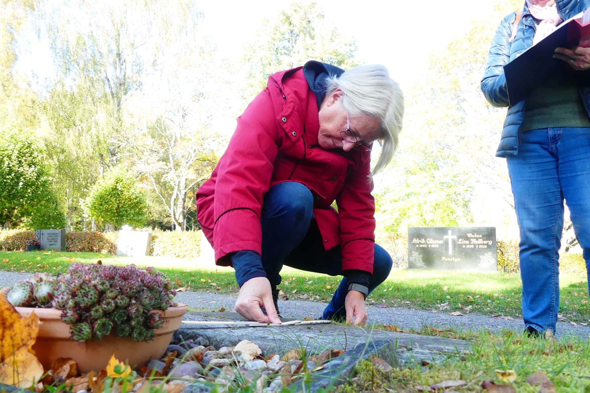 Gunilla Bivall (röd jacka) leder den pågående gravstensinventeringen på Fröskogs kyrkogård. 