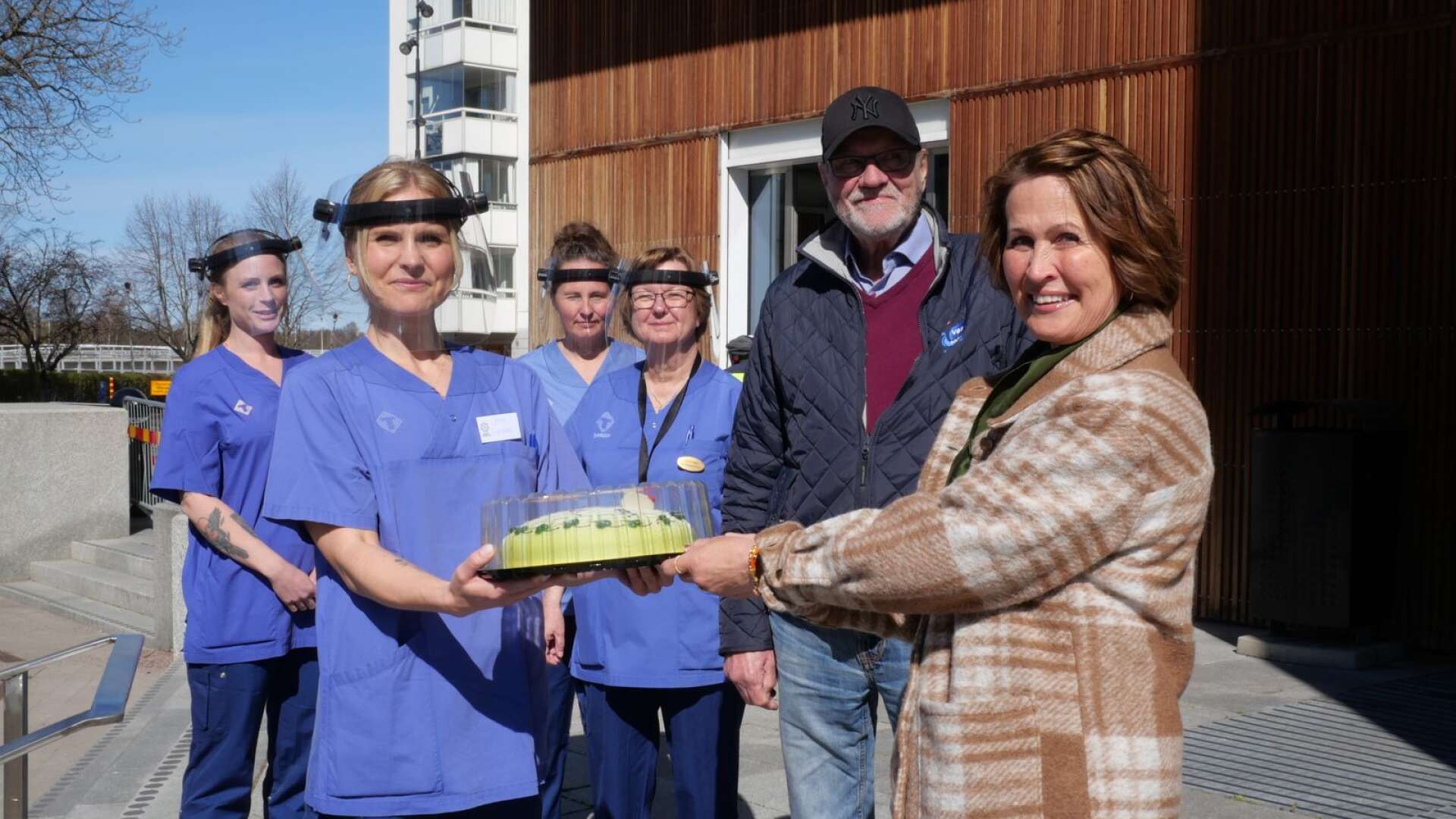 Torsten Born, vice ordförande PRO Värmland och Anneli Borg Lundgren, vd Coop Värmland, lämnar över tårtor till vaccinatörer utanför Karlstad CCC.
