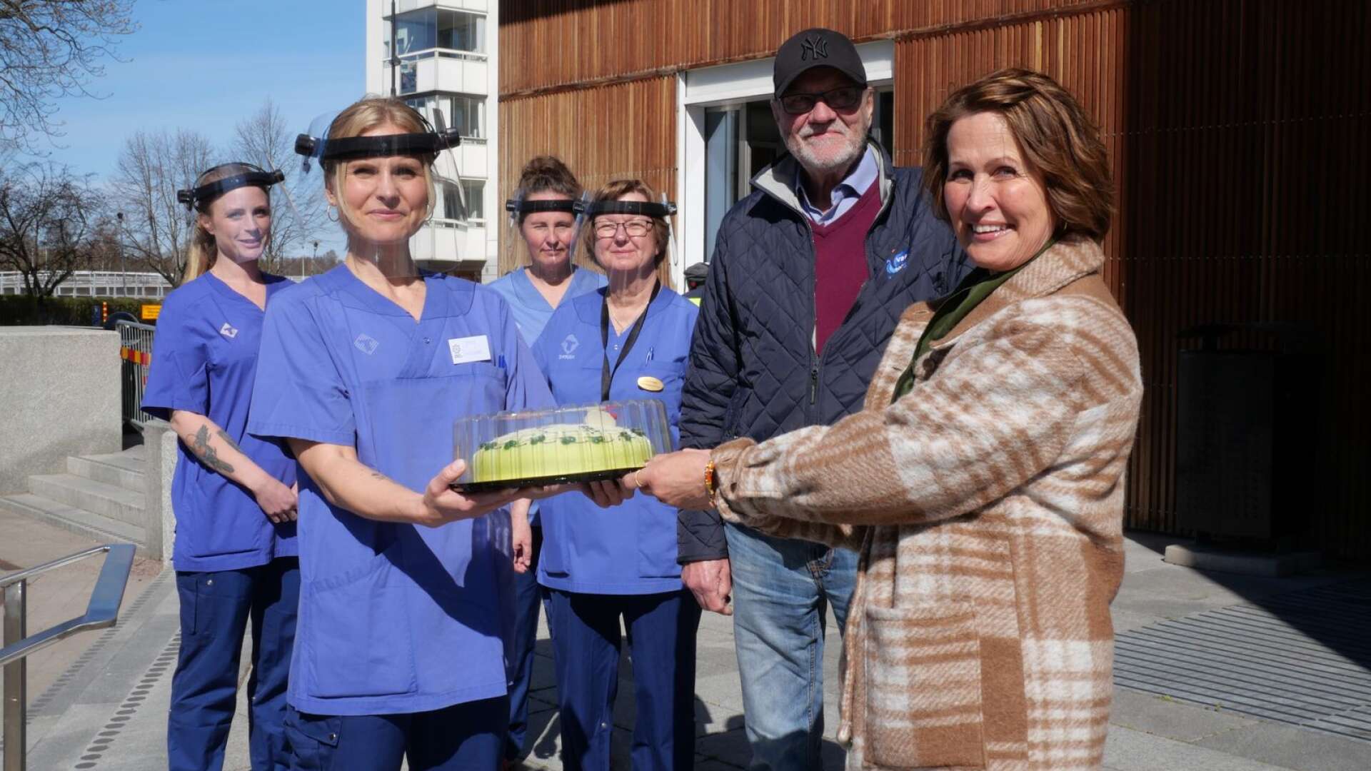 Coop Värmlands vd Anneli Borg Lundgren och PRO Värmlands ordförande Thorsten Born överlämnar tårta till Jenny Aschberg, Ing-Marie Carlsson, Marie Nordin och Sofie Wallquist, som jobbar med vaccination på Karlstad CCC. 