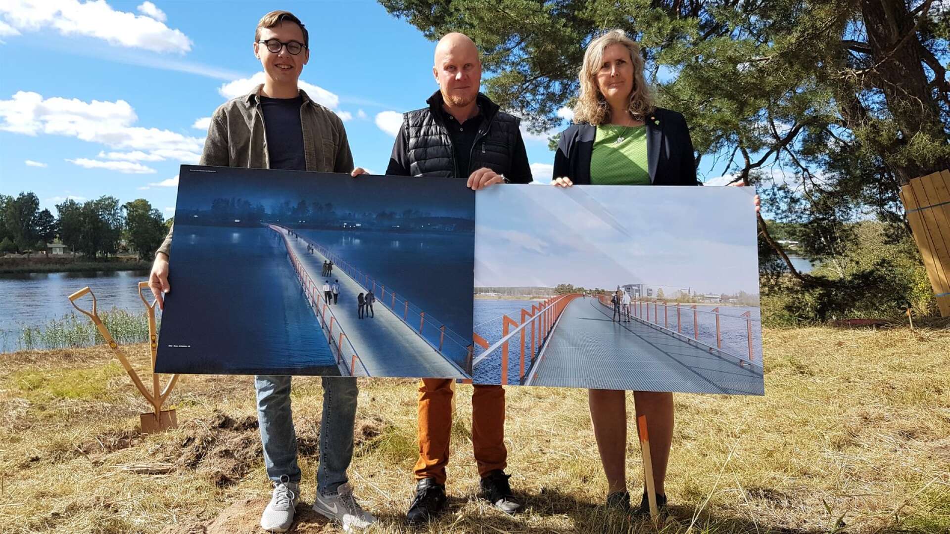 Politikerna Alexander Torin (M), Henrik Lander (C) och Monika Bubholz (MP) visar hur den nya gång- och cykelbron mellan Råtorp och Färjestad ska se ut. På illustrationerna saknas den ramp som ska underlätta för hundar.