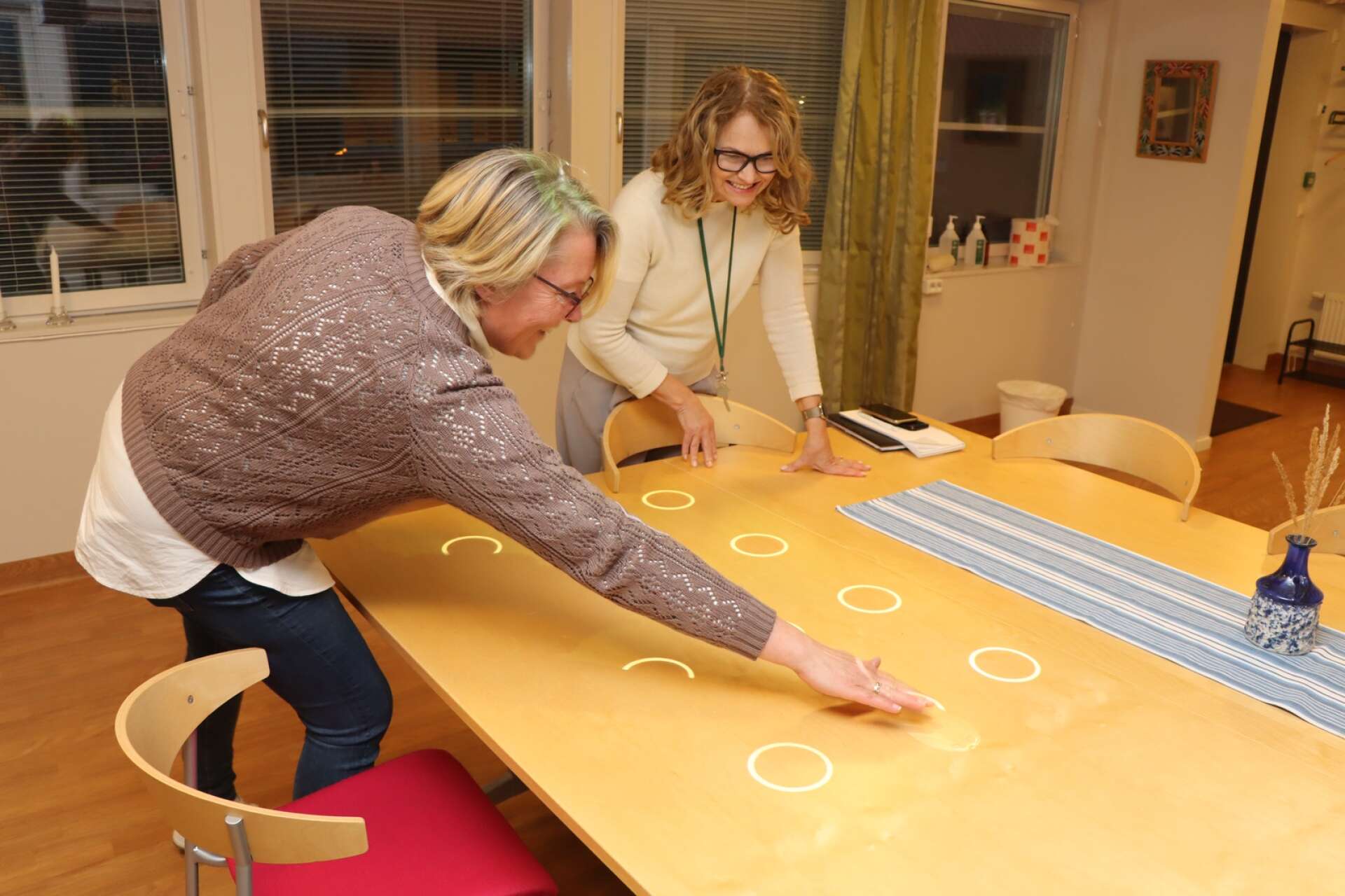 Helena Lundgren Kiss och Susanne Ljungberg provar ett av de många spelen på spelkonsolen Tovertafel, vars bilder projiceras på ett bord och som känner av spelarnas handrörelser.