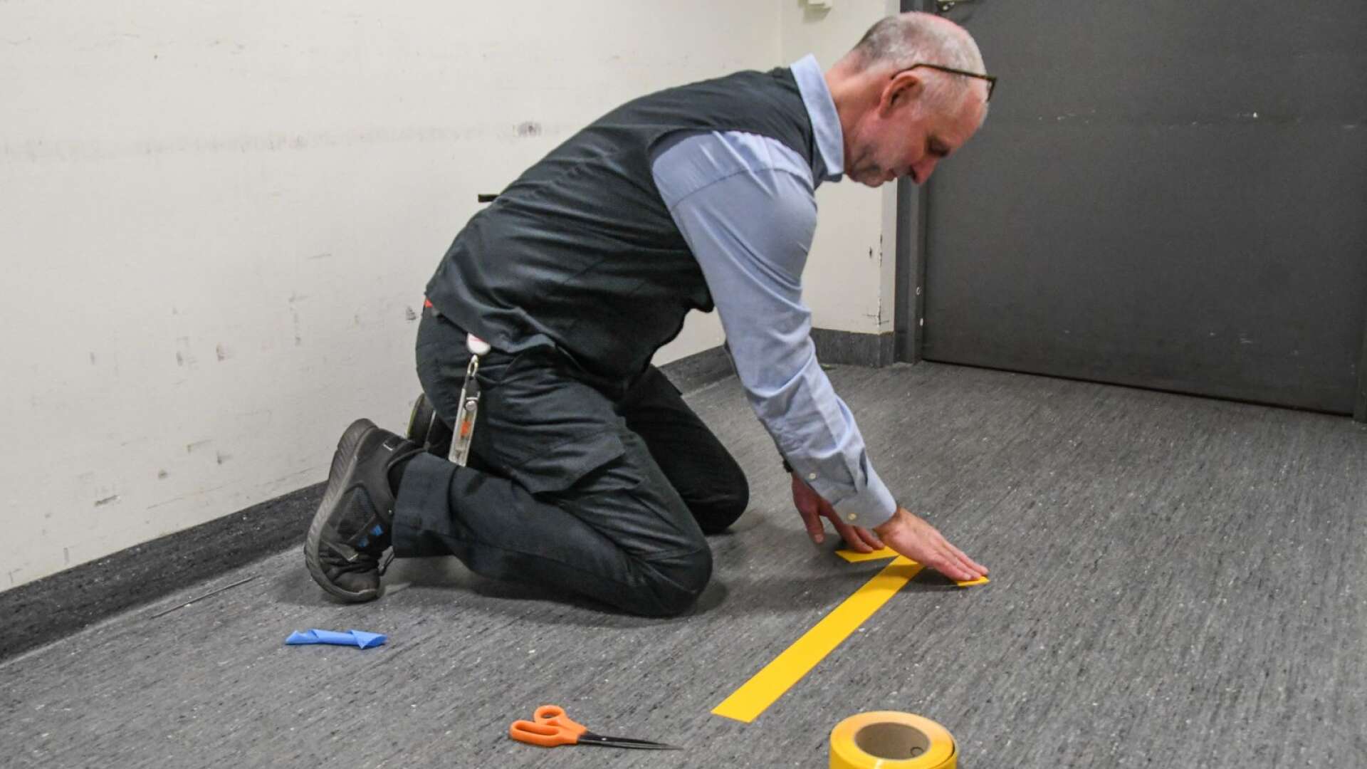 Icahandlaren Jan Andersson tejpar stor pilar på golvet för att visa att kunderna ska gå ut en annan väg än de kommer in. 