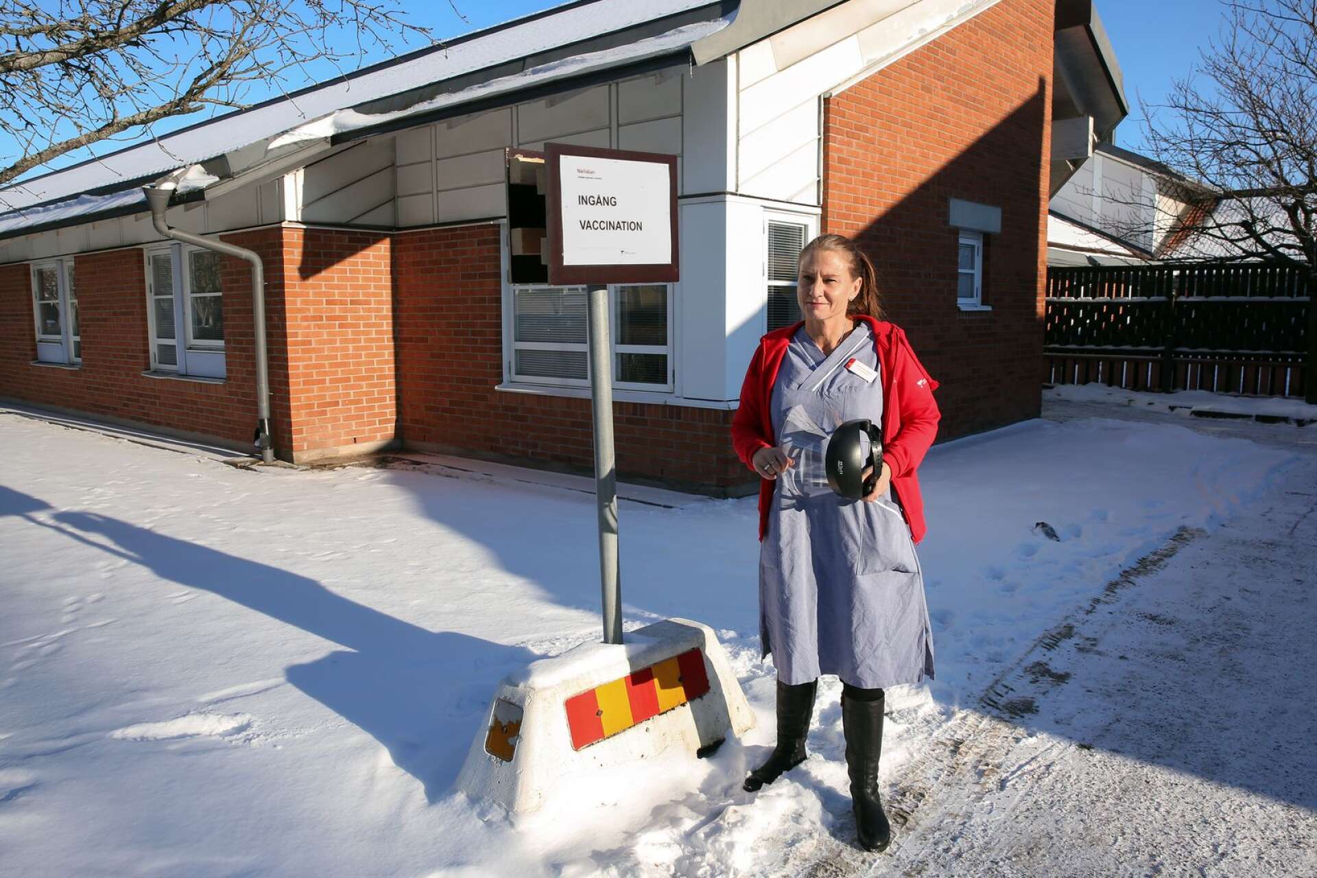 Vårdcentralschef Petra Aronsson vid skylten som visar ingången för dem som ska vaccineras.