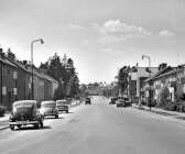 Så här såg det ut på Karlstadsvägen på 1950-talet. De flesta av dessa hus var byggda andra hälften av 1940-talet. När bilden togs hade planterade buskar och träd börjat växa till sig. Längst bort vid vägens slut kan man skymta gamla busscentralen. 