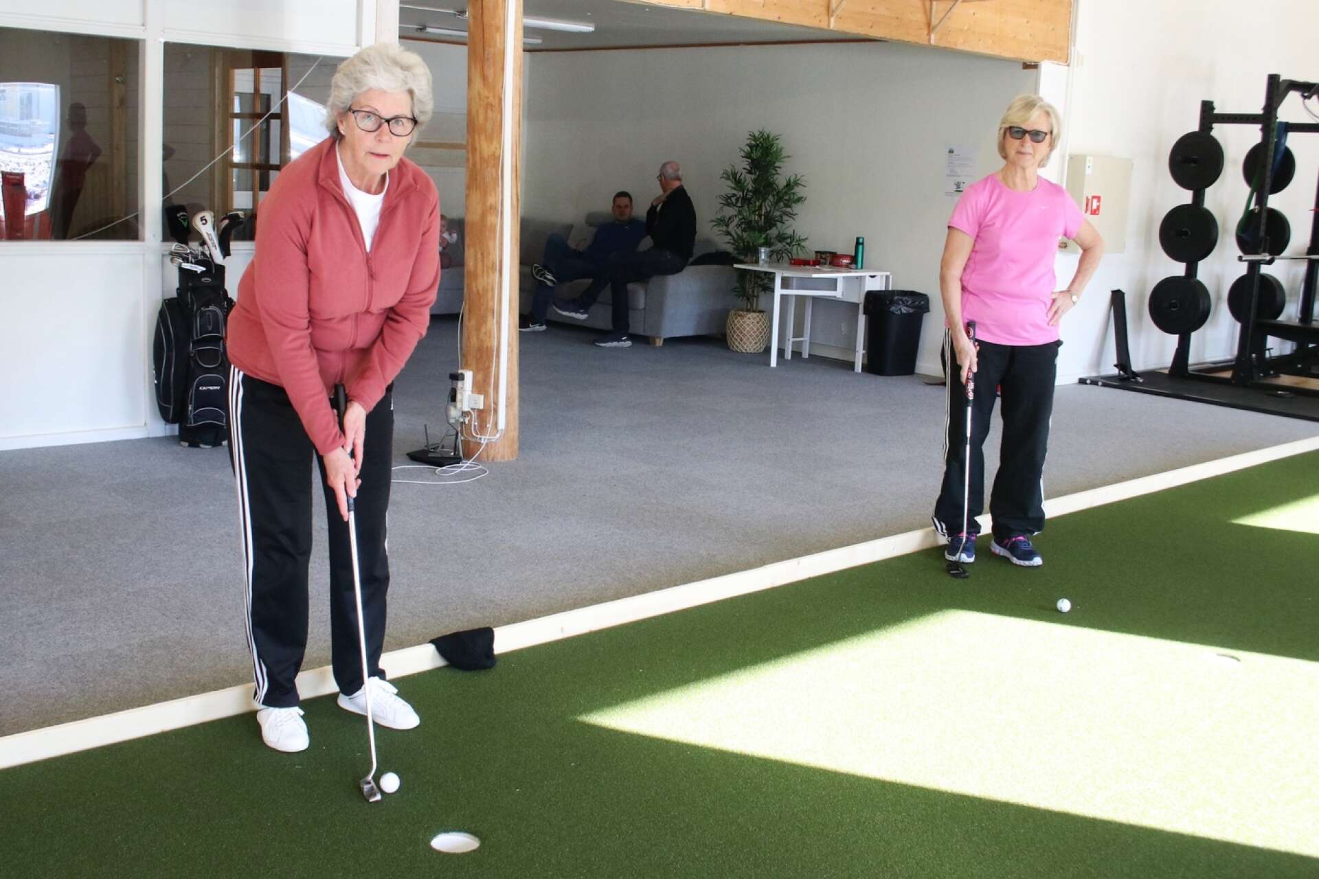 Kerstin Svensson och Kerstin Jansson tränar puttning i golfhallen.