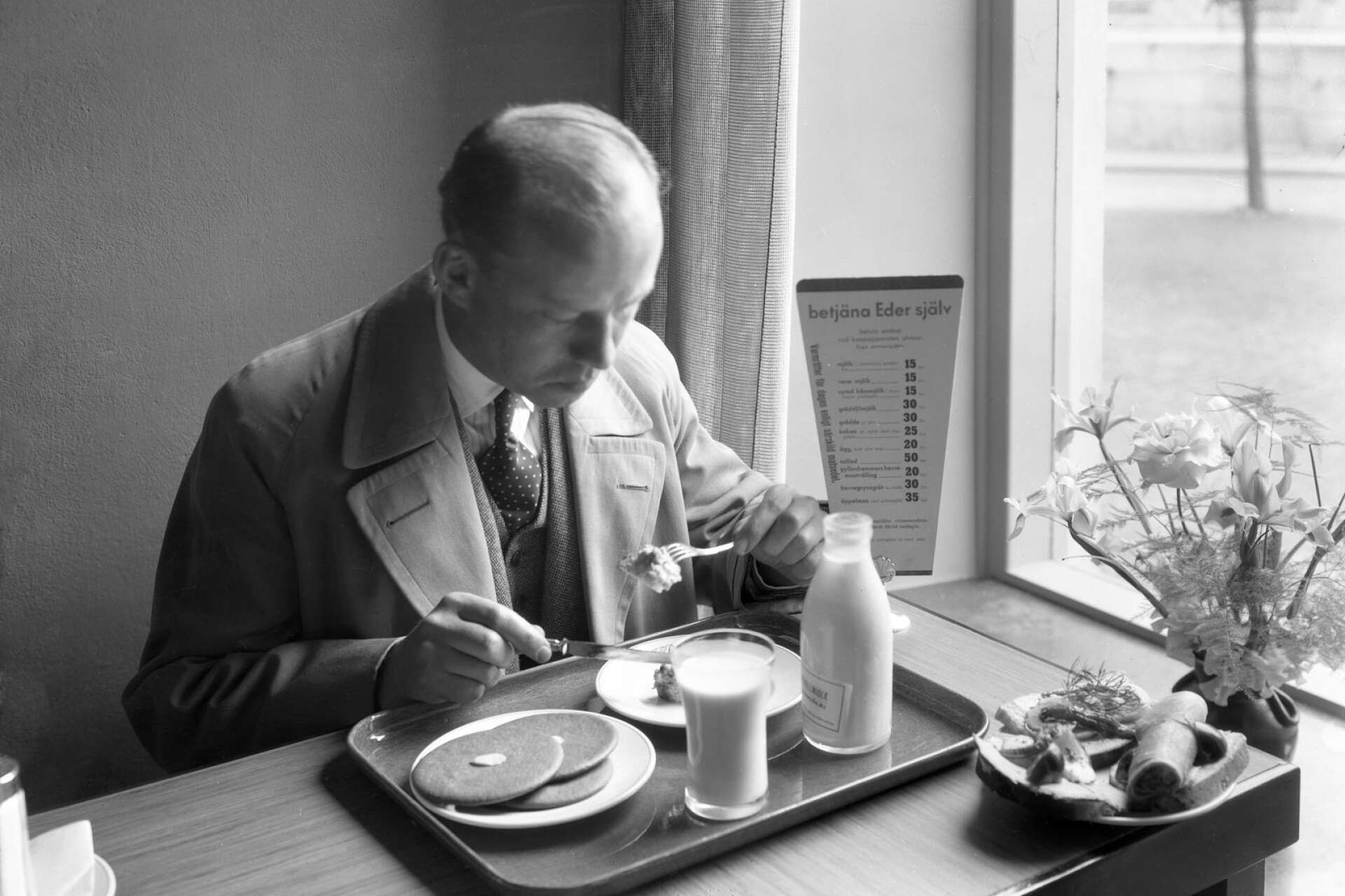 En gäst som äter en rejäl frukost med smörgåsar, plättar och mjölk. Bilden togs 1935.