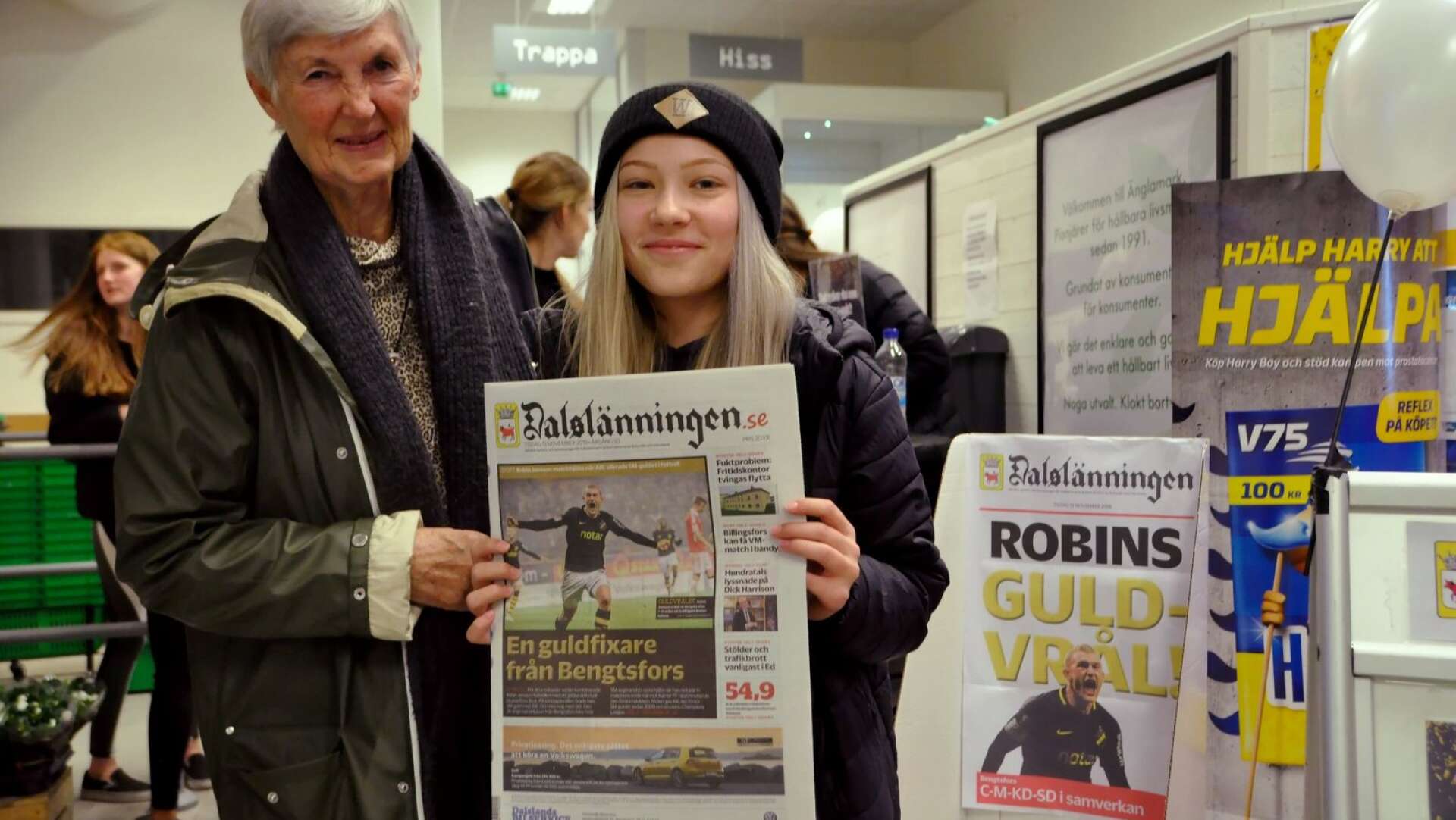 Robin Janssons lillasyster, Maja Jansson, håller upp Dalslänningens förstasida som pryds av hennes storebror när han jublar efter att ha gjort målet som ledde AIK till SM-guld. Vid hennes sida bonusfastern, Inger Karlsson.