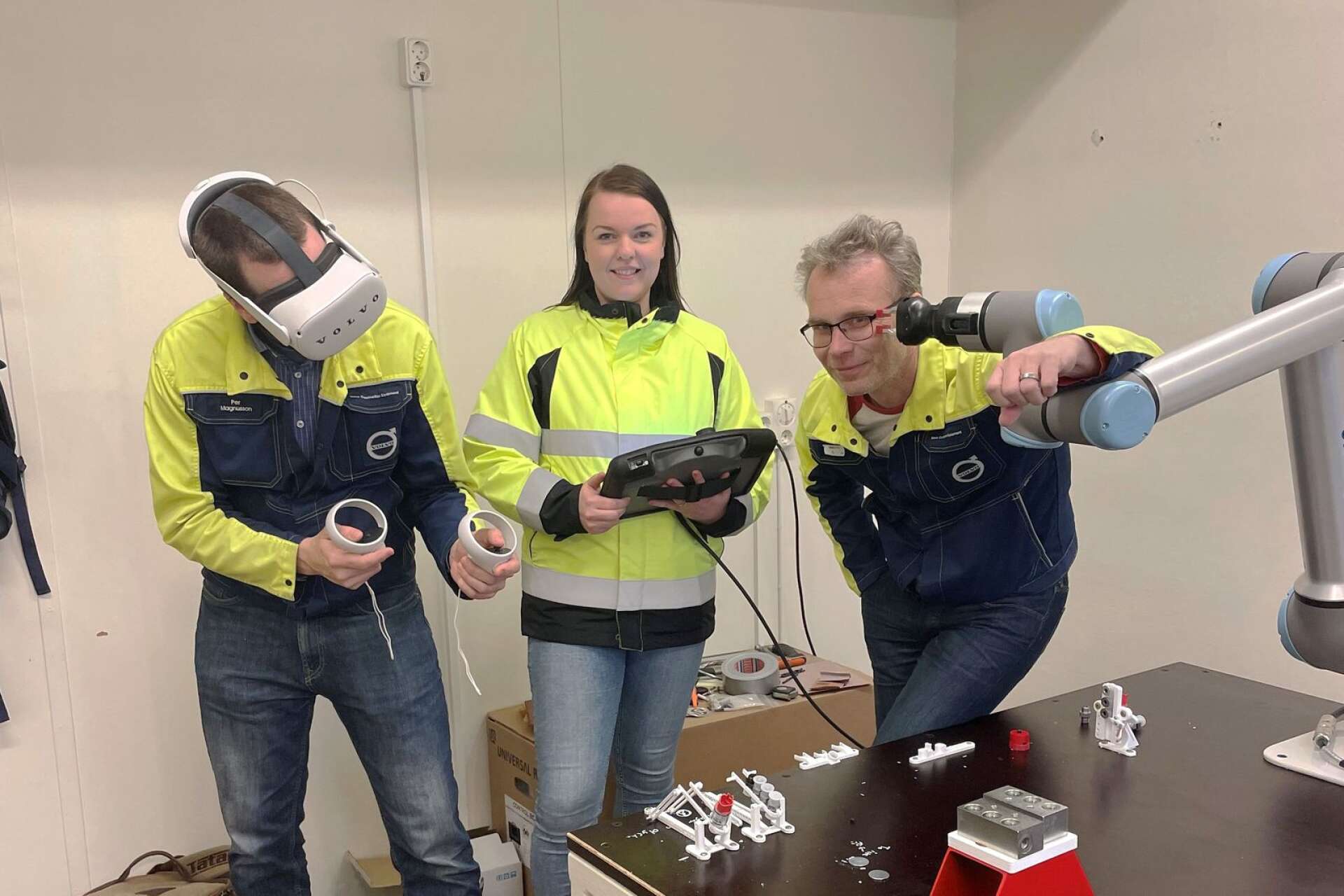 Volvo CE i Arvika bjuder in till heldag där ny teknik visas upp. Här Per Magnusson med VR-utrustning, Anne Bernadette Åhl som styr en robot och Lars Hanson som står vid själva roboten.