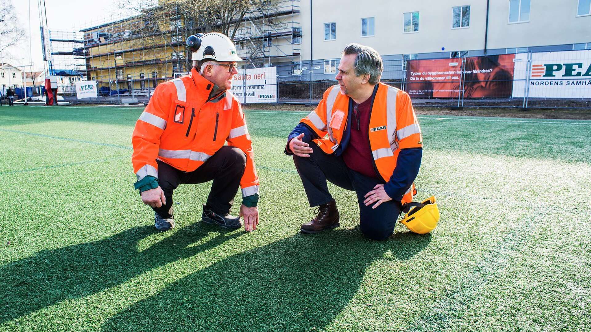 Urban Björklund, plastchef för entreprenören Peab, och kommunalrådet Niklas Wikström (L) tittar till den nuvarande konstgräsmattan på Västerstrand som ska bytas ut i sommar.