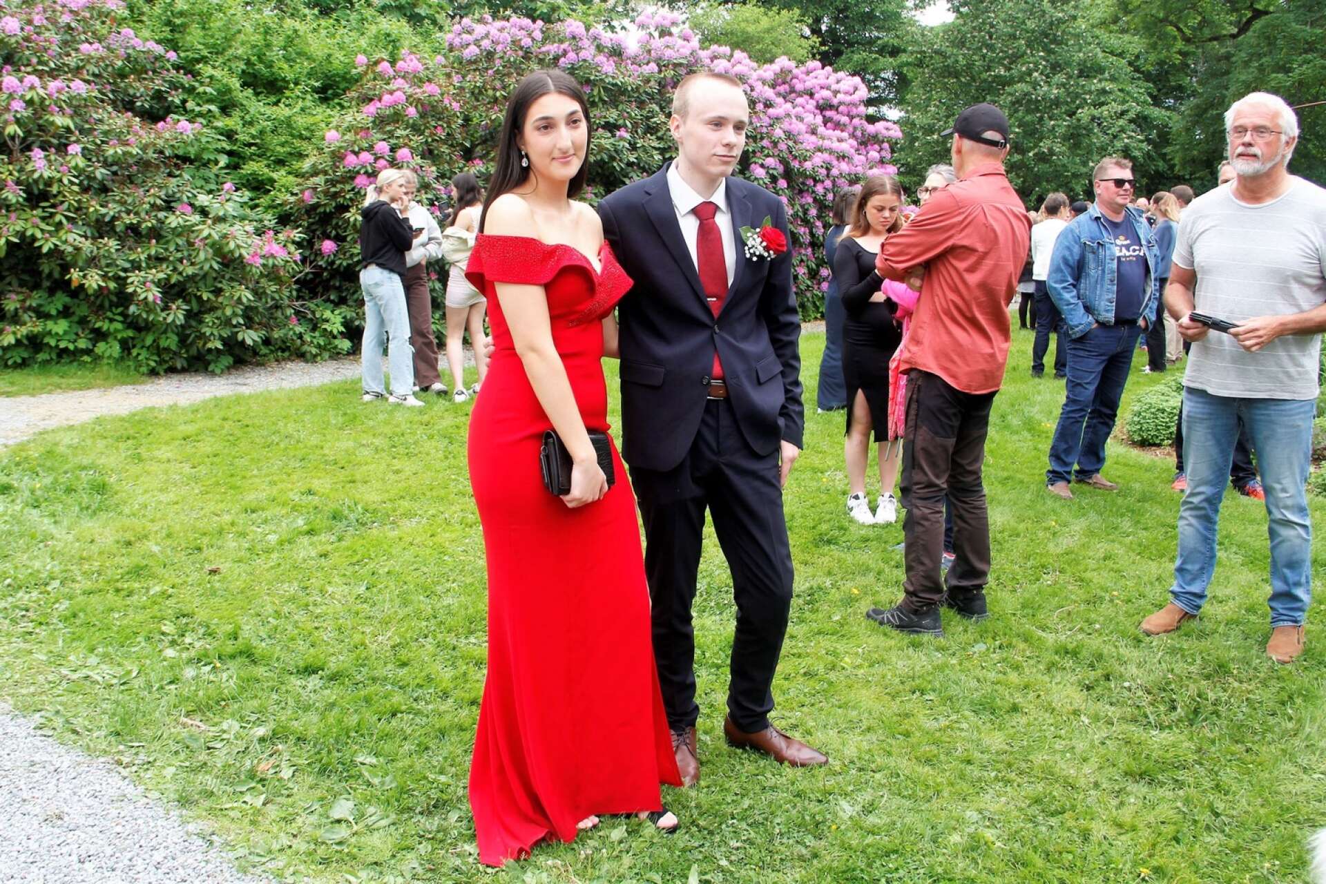 Rafaella Al Homsi i röd långklänning i sällskap med Karl Bergvall med matchande röd ros på kavajslaget.