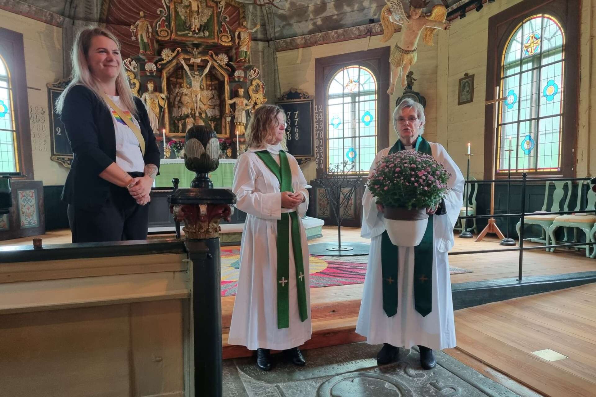 Gunnel Blomgren håller blomman som snart överräcks till Monica Mannberg, i mitten. Till vänster syns kyrkorådets ordförande Johanna Svärd (S).