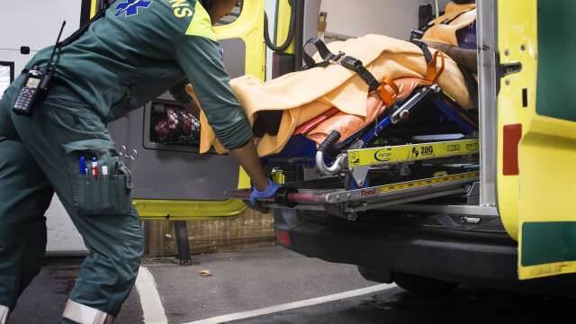 Ambulanssjukvårdare med patient på bår i ambulans.