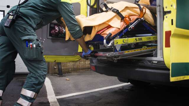 Ambulanssjukvårdare med patient på bår i ambulans. Genrebild.