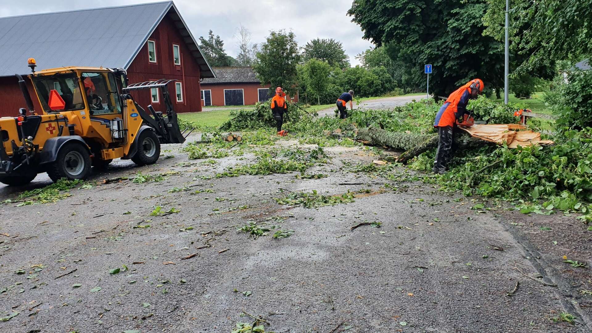 Joakim Björk i lastmaskinen och Anna Karlsson, Toralf Alexandersson och Carl Hamnström jobbar med att få bort trädet som föll över vägen vid vandrarhemmet i Varnhem.