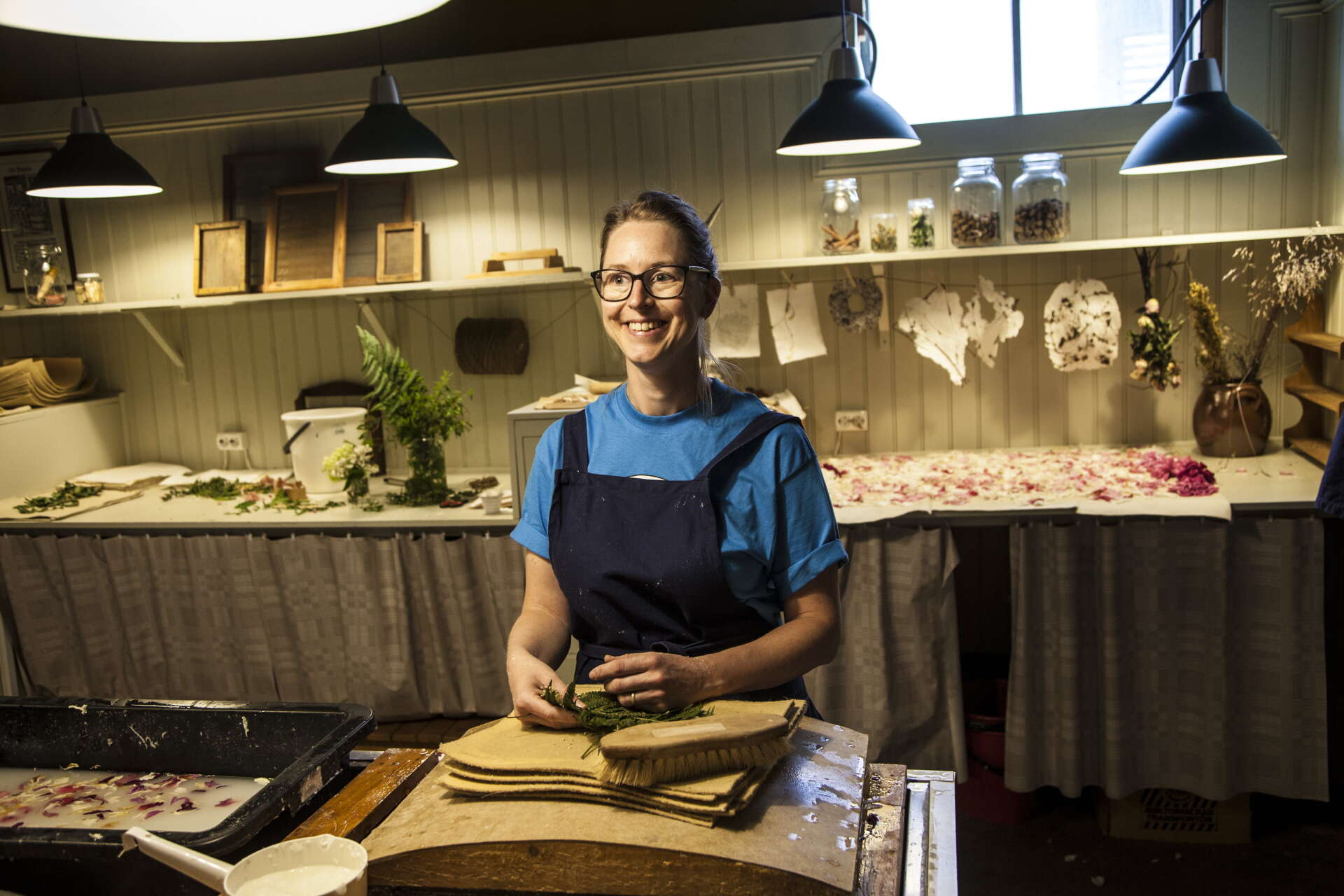 Pedagogen Pernilla Hjelt hjälper besökarna på Frövifors pappersbruksmuseum att göra eget handgjort papper med inslag av torkade blommor.