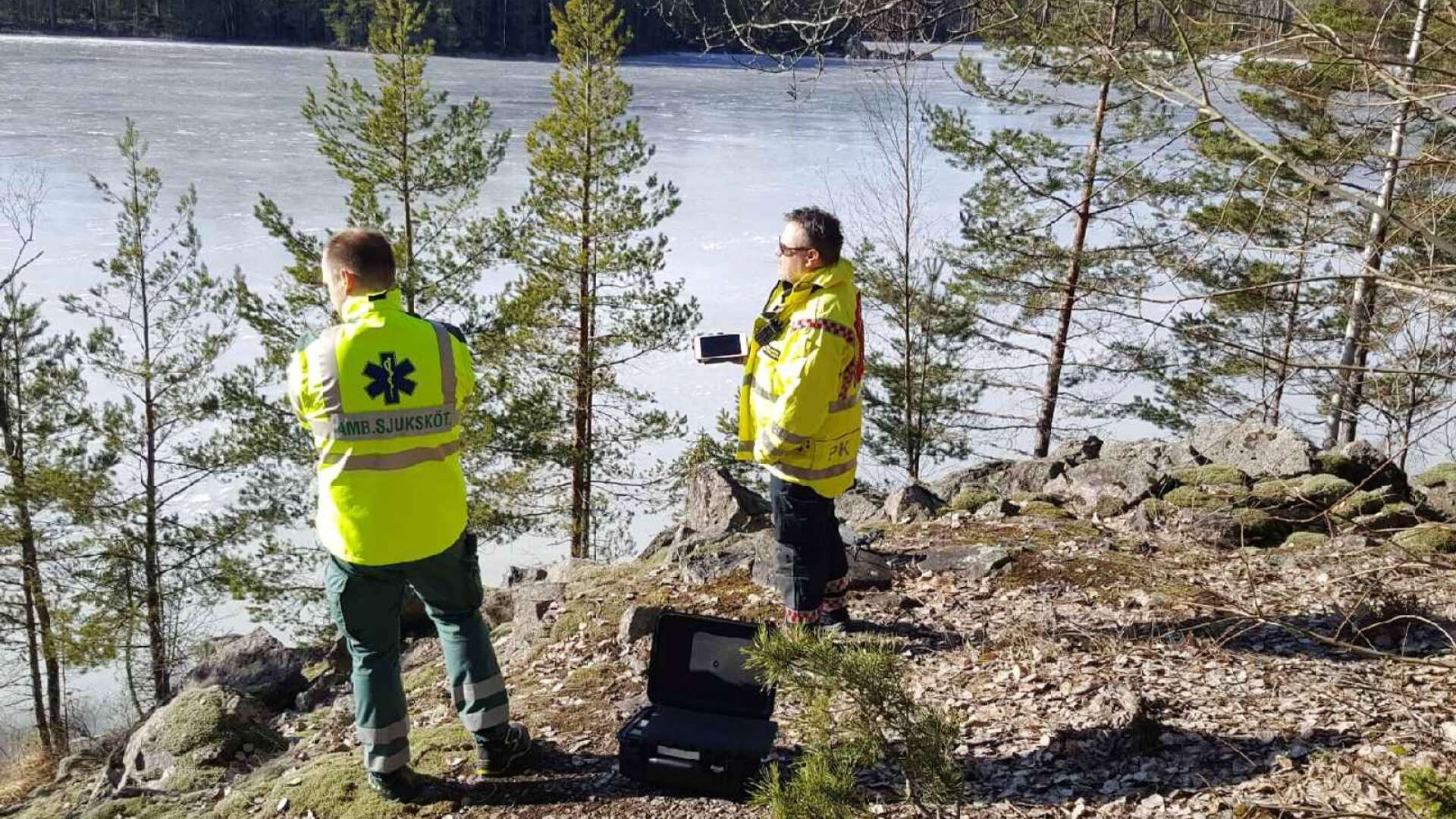 Insatsledaren Peter Karlsson (till höger) blickar ut över Abborrtjärns is tillsammans med personal från ambulansen.