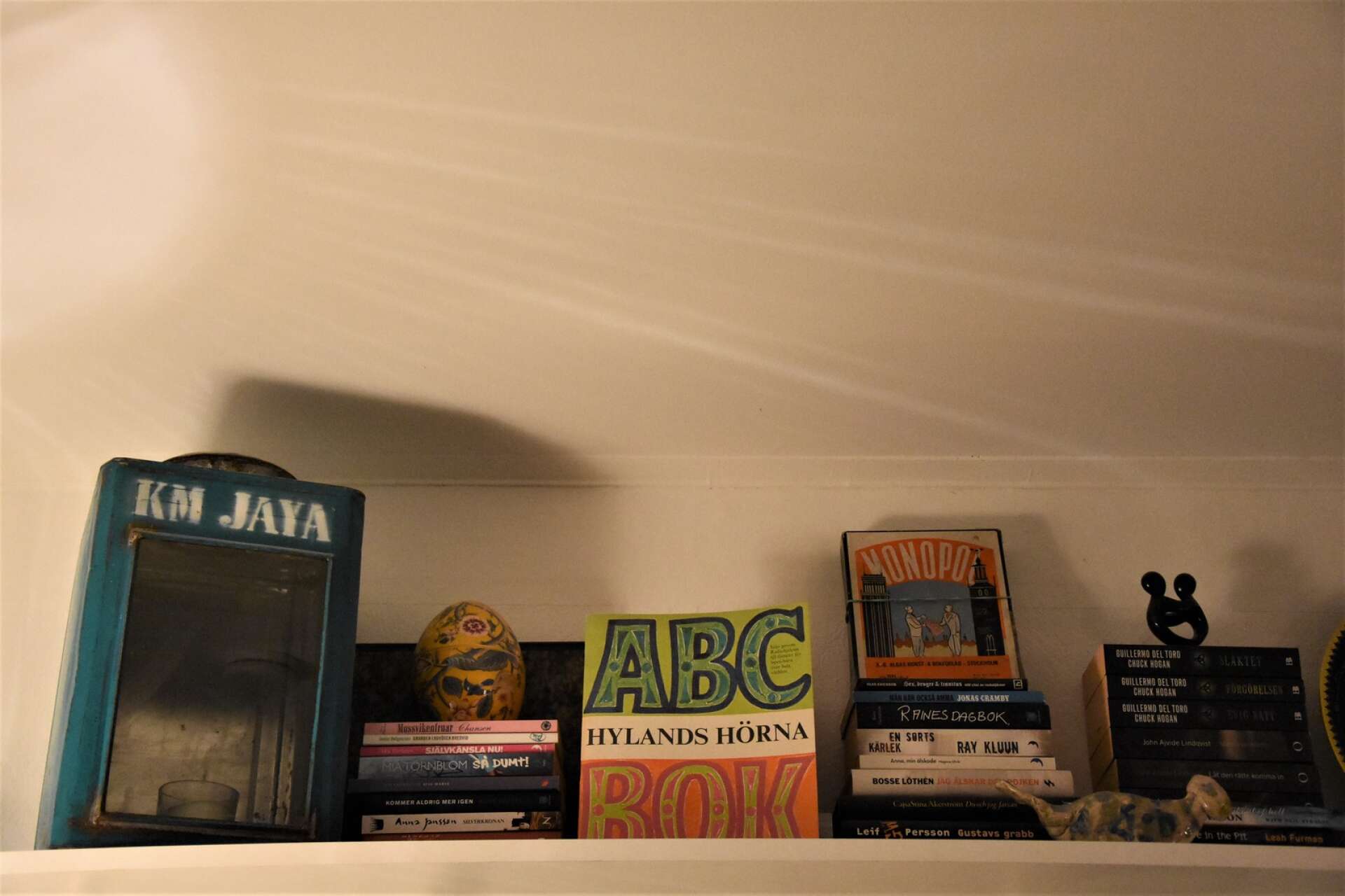 Vägghyllan inrymmer böcker, spel och prylar från olika tidsepoker