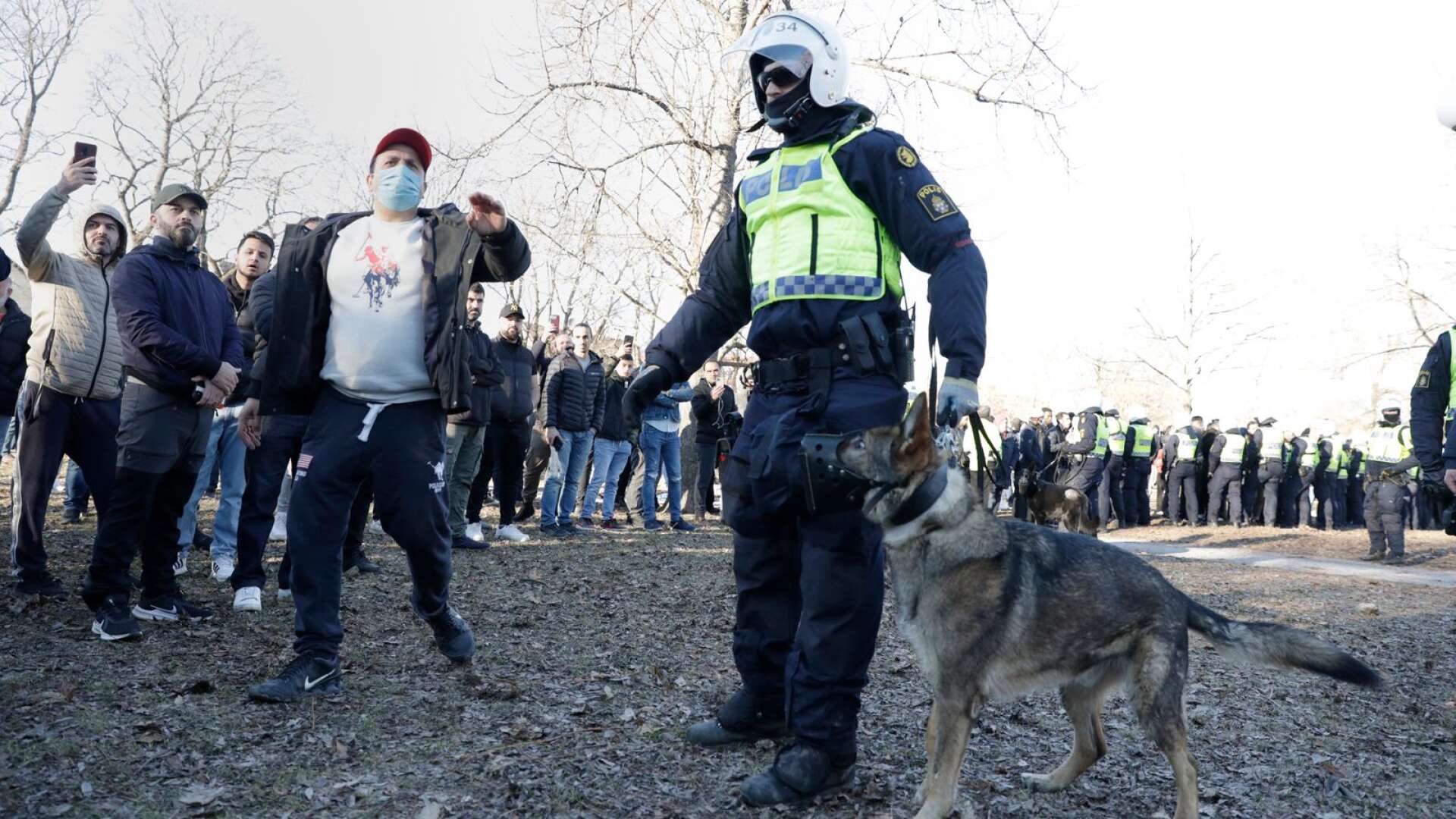 En polis med polishund och motdemonstranter i Sveaparken i Örebro, där Rasmus Paludan, partiledare för det danska högerextrema partiet Stram kurs, fick tillstånd för en sammankomst på långfredagen. Arkivbild.