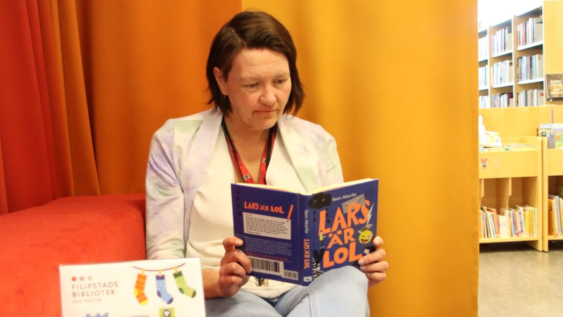 Under rocka sockorna-dagen, som hölls i förra veckan, kunde barn- och ungdomsbibliotekarien Josefine Berg Julén plocka fram aktuella tips. Här sitter hon och läser boken Lars är LOL av Iben Akerlie.