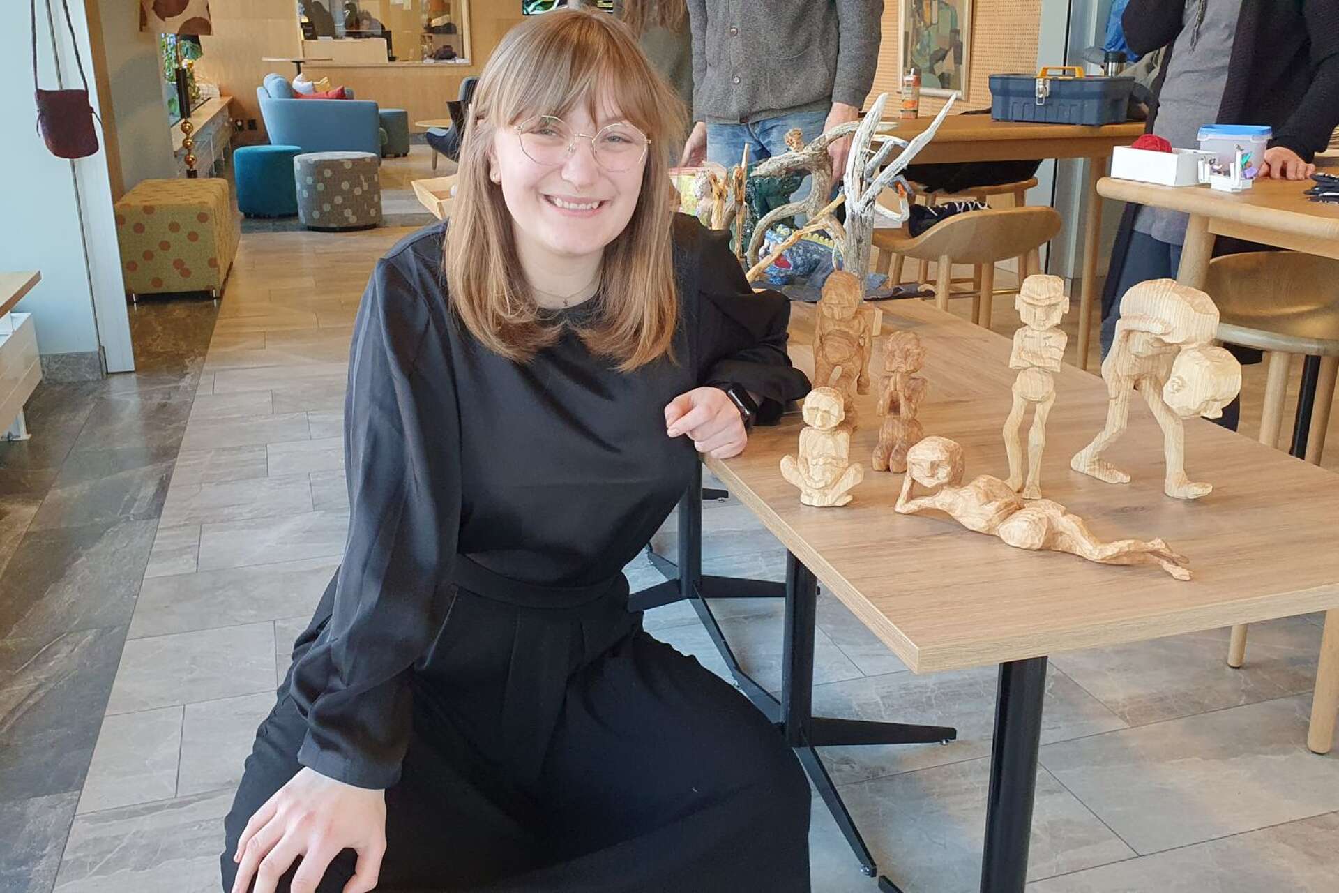 Molly Bergman vid de träskulpturer hon har täljt och bidrar med till utställningen.