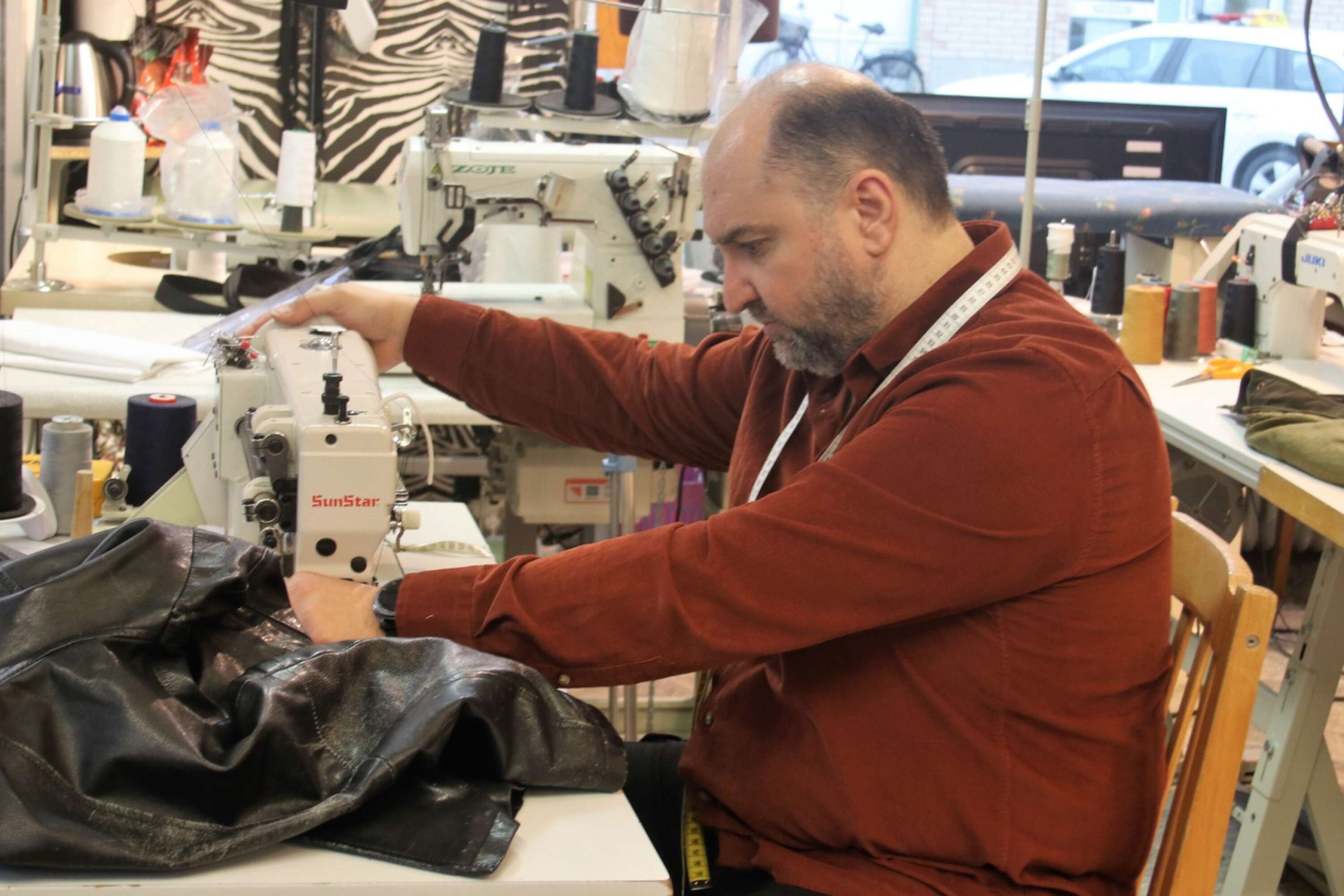 Ahmad Nana har tillgång till kraftfullare symaskiner än de som oftast finns i hemmen. Här byter han dragkedja på en skinnjacka.
