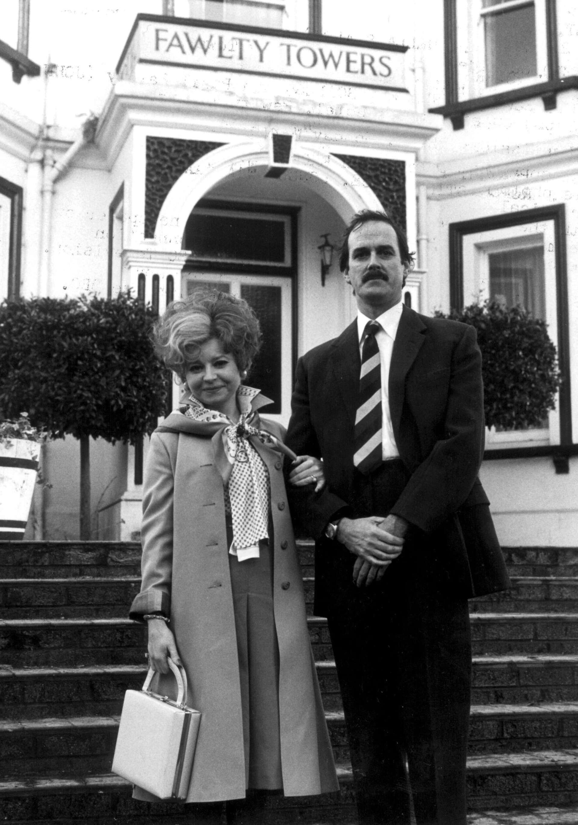 Här ses Prunella Scales som Sybil Fawlty och John Cleese som Basil Fawlty utanför hotellet Fawlty Towers i Torquay på engelska sydkusten.