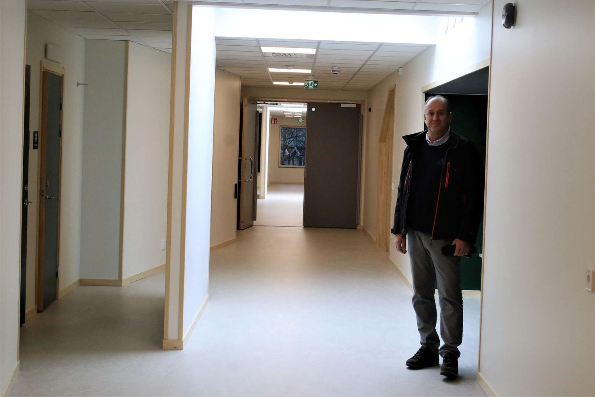 Magnus Dalsbo står i en av skolans huvudkorridorer med lätt välvda väggar.