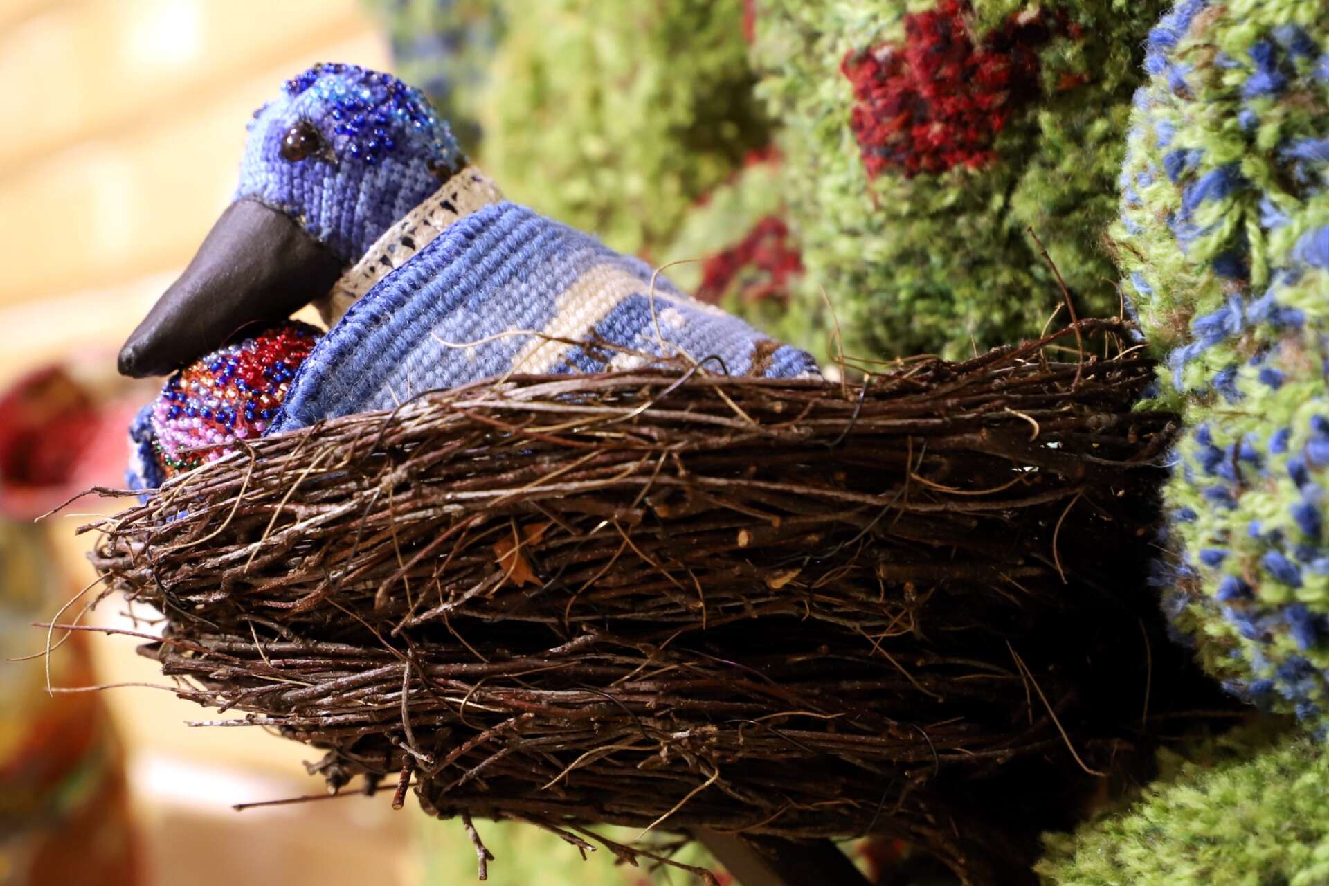 En fågel i sitt trygga bo. Annika Eriksdotter skapar textilskulpturerna med inbjudande garnmossa.