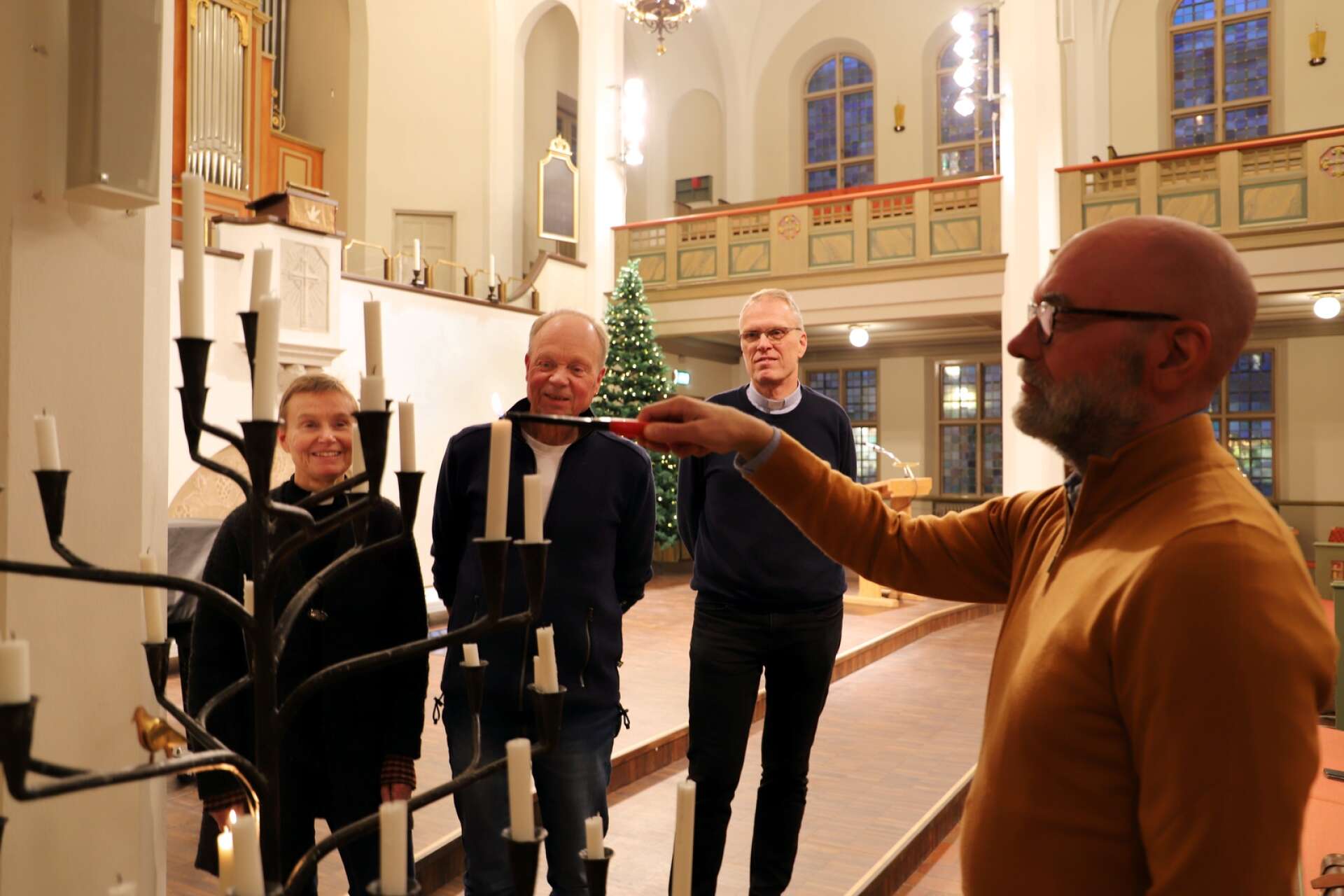 Nils Erik Hagström tänder ljus i kyrkorummet, där han och Anneli Sandberg, Anders Göranzon och Per-Ulrik Johansson hoppas få möta många sjungande besökare på onsdag, den 21 december.