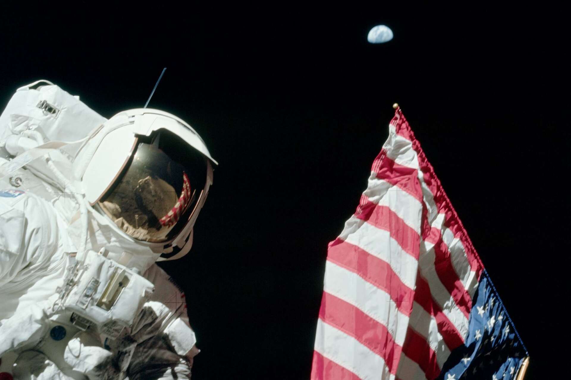 Jack Schmitt vid amerikanska flaggan med Jorden ovanför.