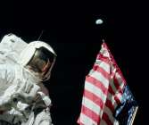Jack Schmitt vid amerikanska flaggan med Jorden ovanför.