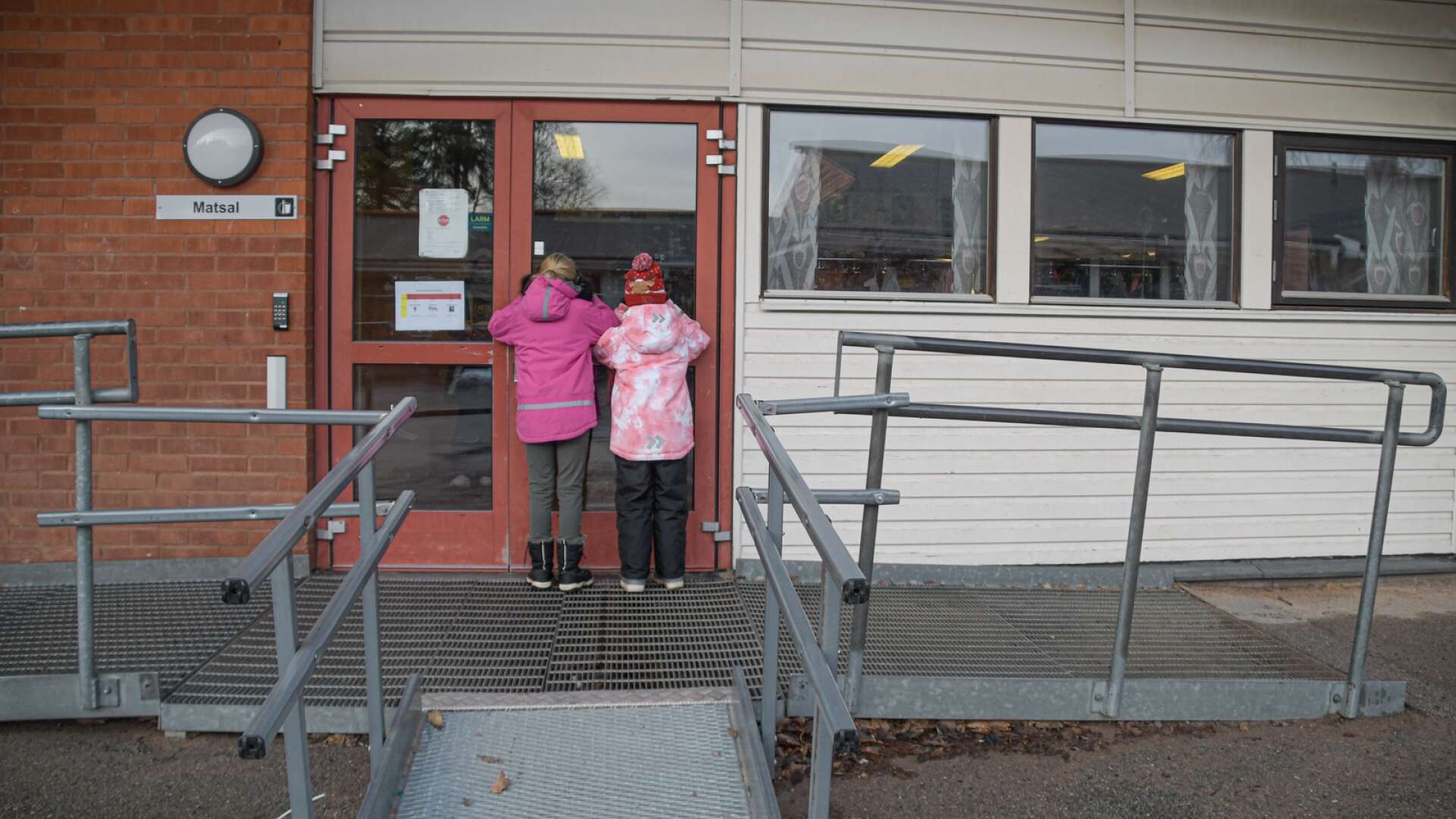 Två små tjejer kikar in genom dörrarna till Kilenskolans matsal. Här kommer alla barn på avdelning Galaxen som har morgonfritids att äta frukost från och med den  21 februari. 