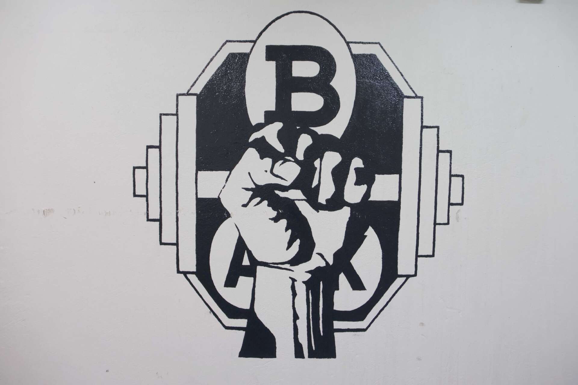 Bäckefors Atletklubbs logga är skapad av Kristoffer Ling-Johansson och finns målad på väggen i källarvalvet.