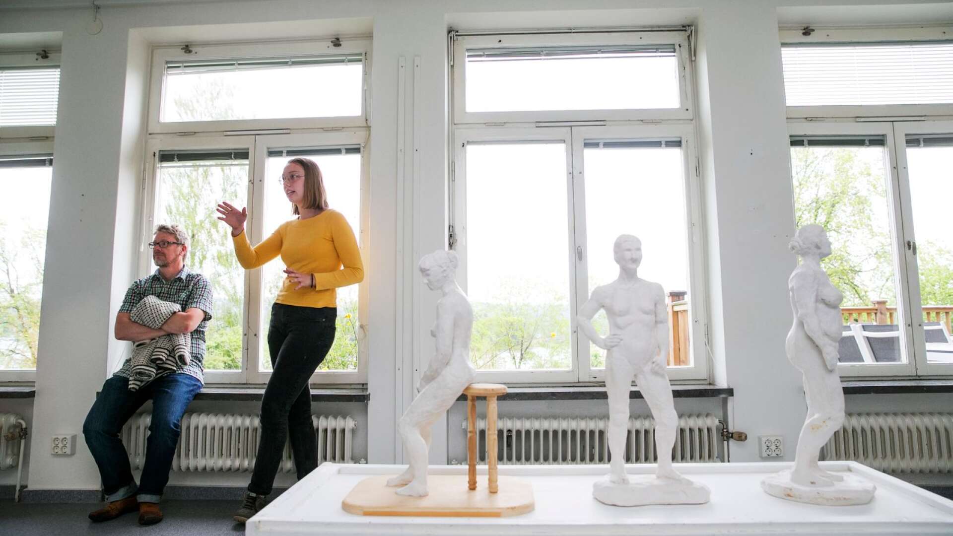 Elsa Bernholm visar upp sin krokiutställning i utställningsrummet på Kyrkeruds folkhögskola. Den visas inte upp under helgens vårutställning. I fönstret sitter läraren Henric Westlund.