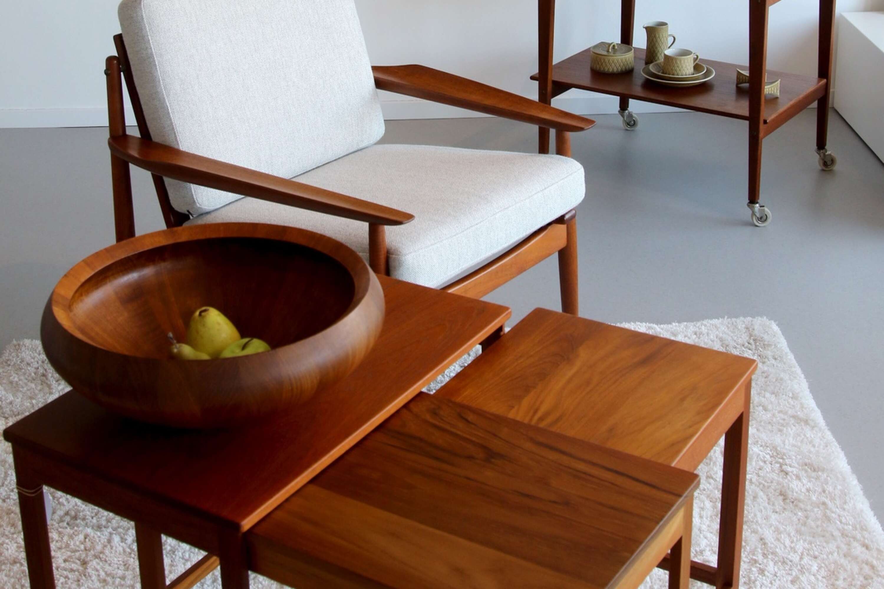 Loungefåtöljer i teak i design av Arne Vodder, bord av Peter Hvidt och Orla Molgaard Nielsen samt skål i trä av Jens Quistgaard hos Deco och design.