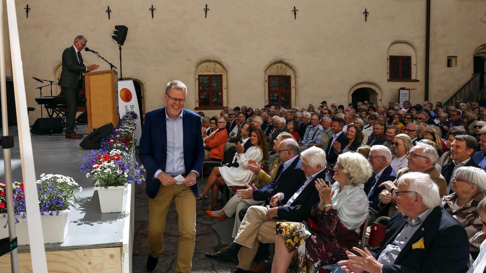 En glad Jan Malmgren, vd för Stiftelsen Läckö Slott, kliver upp på scenen för att presentera årets sommarevenemang.