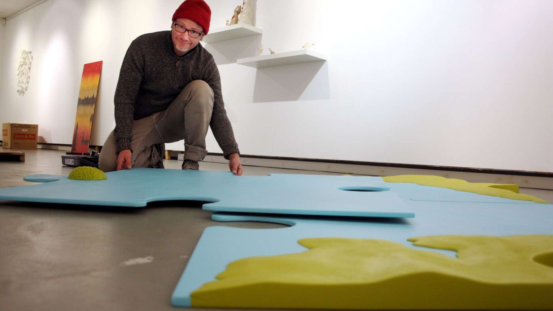 Konstnären Henric Westlund lägger pussel i sin del av utställningen på Sundsbergs gård i Sunne.