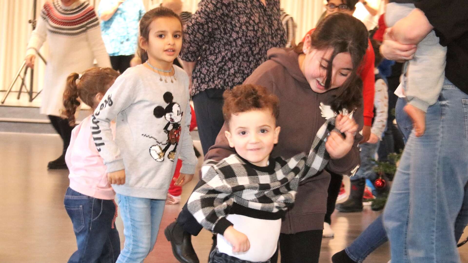 Ahmed Alothman dansade runt granen tillsammans med Dania Alnami och, till vänster, Aseel Alrefaee när det i söndags var dags för julgransskakning i Åmåls församlingshem.