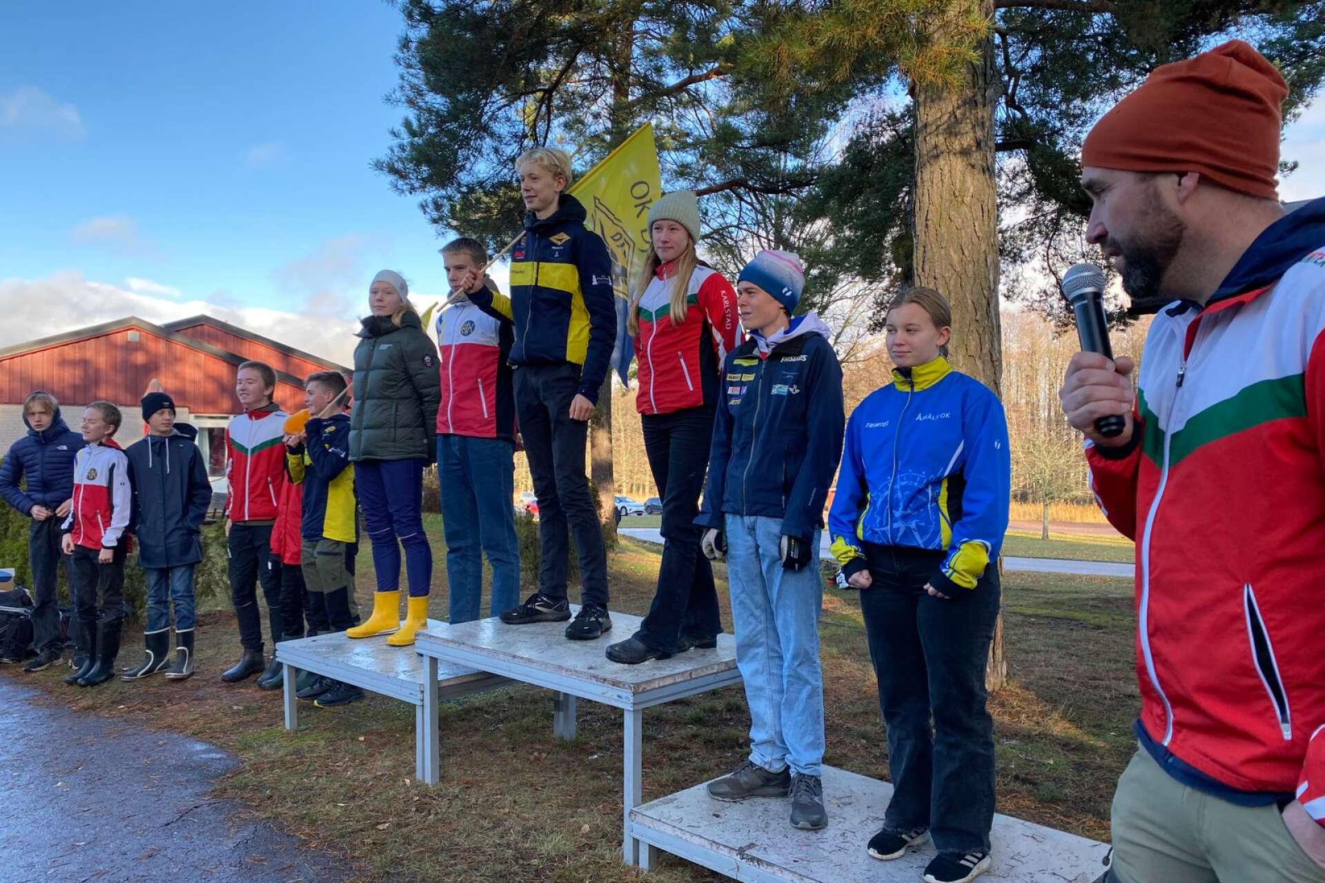 Prispallen i 16-årsklasserna vid Lången som avgjordes i skogarna söder om Sätterstrand på Hammarö. Överst står Izabella Ljungberg, OK Tyr och Edvard Pelander från OK Djerf. Till höger prisutdelaren och ordförande i OK Tyr Martin Ljungberg.