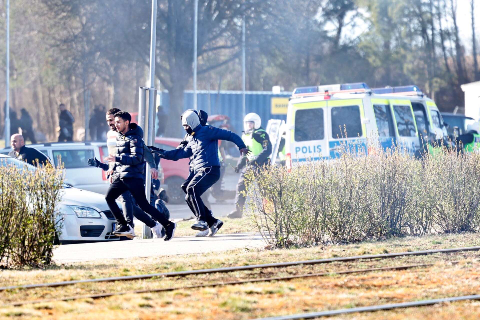 Personer springer från kravallutrustad polis i samband med upploppen i Norrköping på påskdagen.