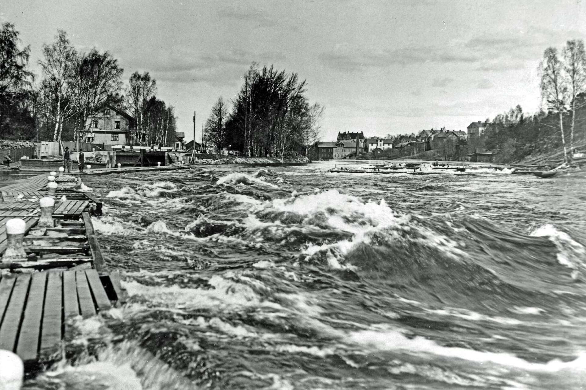 Byälvens vatten forsade delvis över den gamla ledarmen söder om slussen. Året var 1904. Det var översvämning. Då bar fotograf Ludvig Åberg sin stora lådkamera med stativ ytterst på ledarmen och tog denna bilden. Förmodligen var han rejält våt om benen efteråt.
