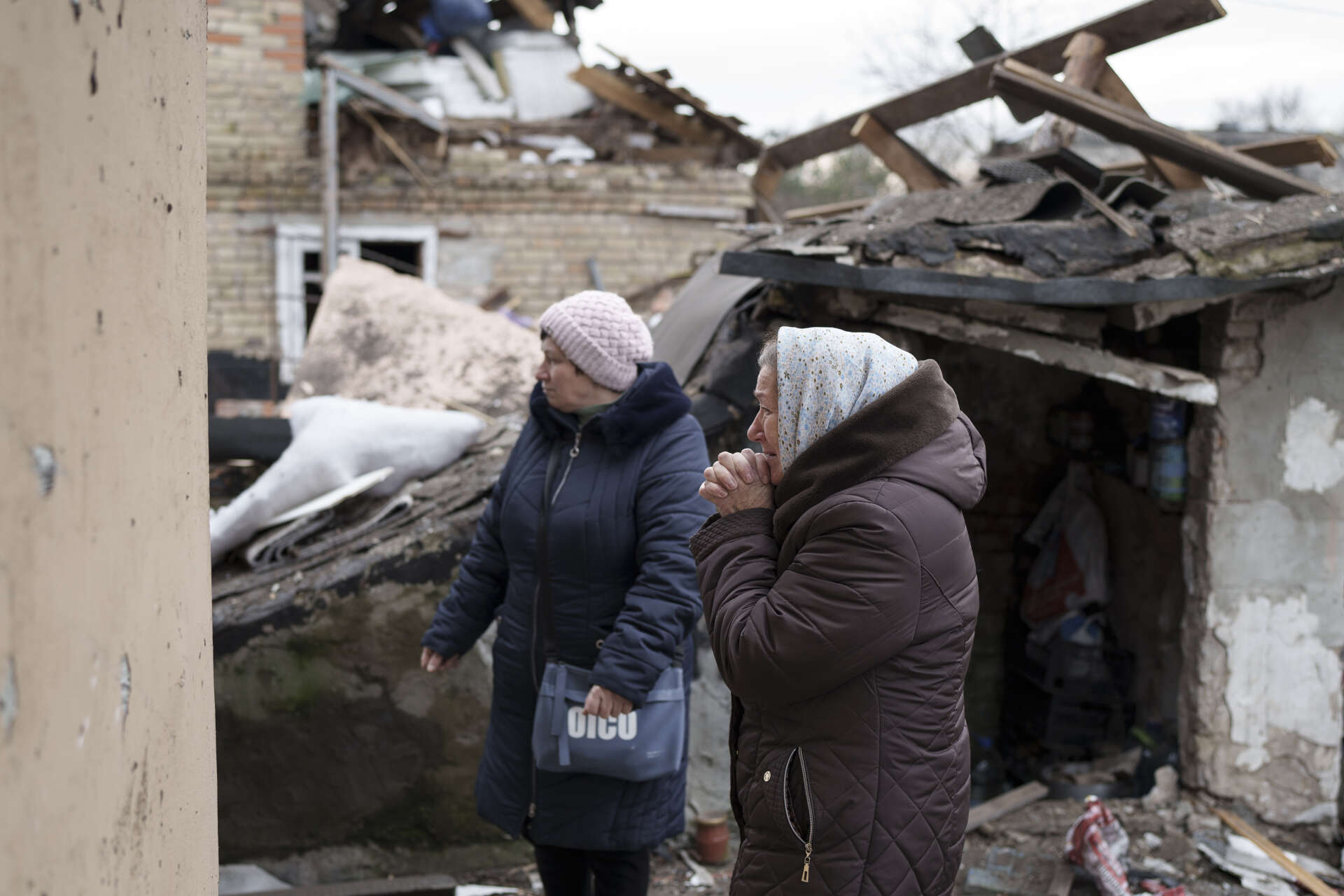 Anhelina, till höger, ser på medan räddningspersonal arbetar i resterna av hennes hus i Kiev som förstördes i de omfattande ryska attackerna i torsdags.