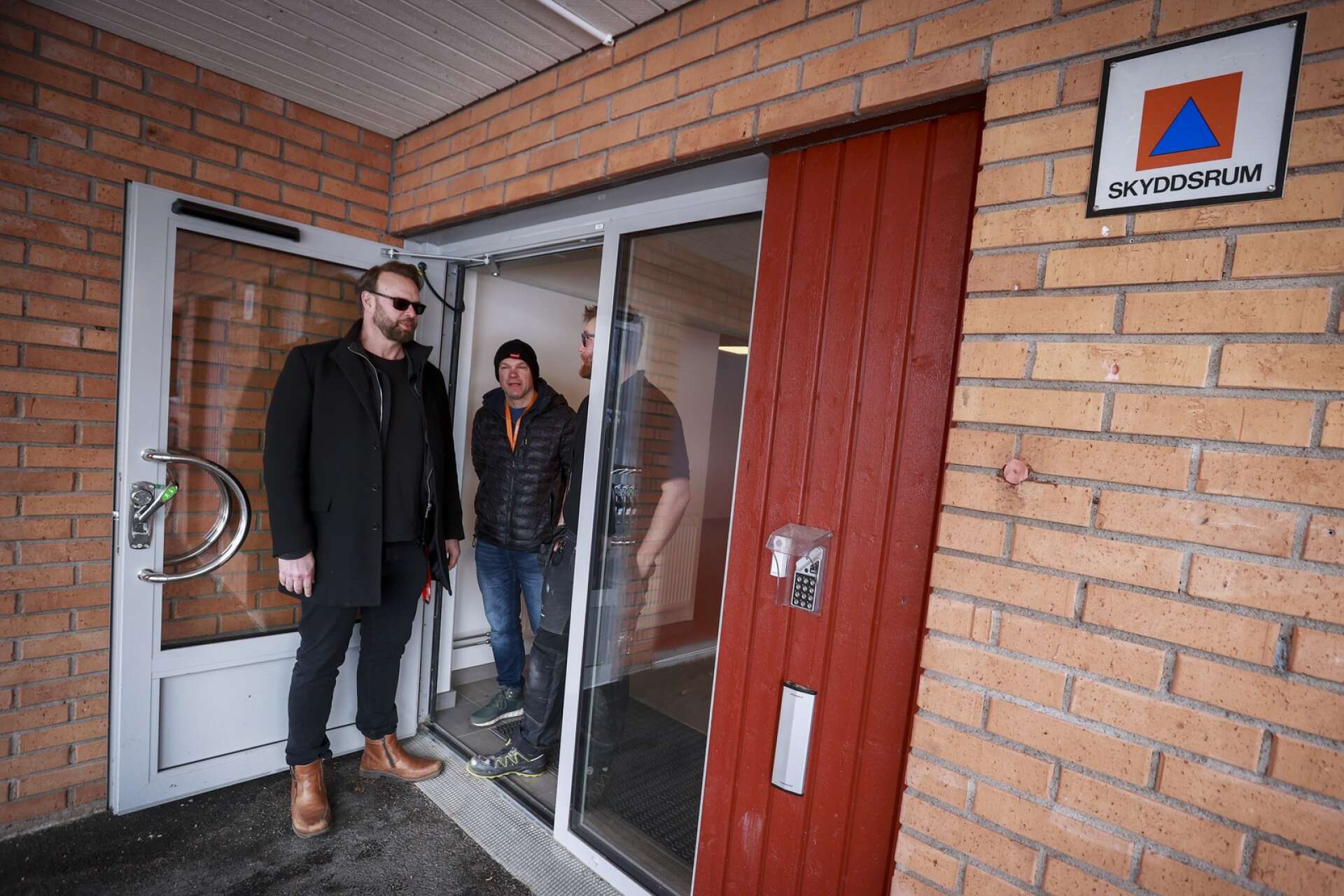 Örjan Rosengren och Tomas Karlsson (och en dold Adam Källvik) vid ingången till Hultsbergsskolans skyddsrum. Vid höjd beredskap låses dörren upp, men skulle rummen inte vara tillgängliga när krisen kommer ”får man forcera dörren”, säger Tomas.